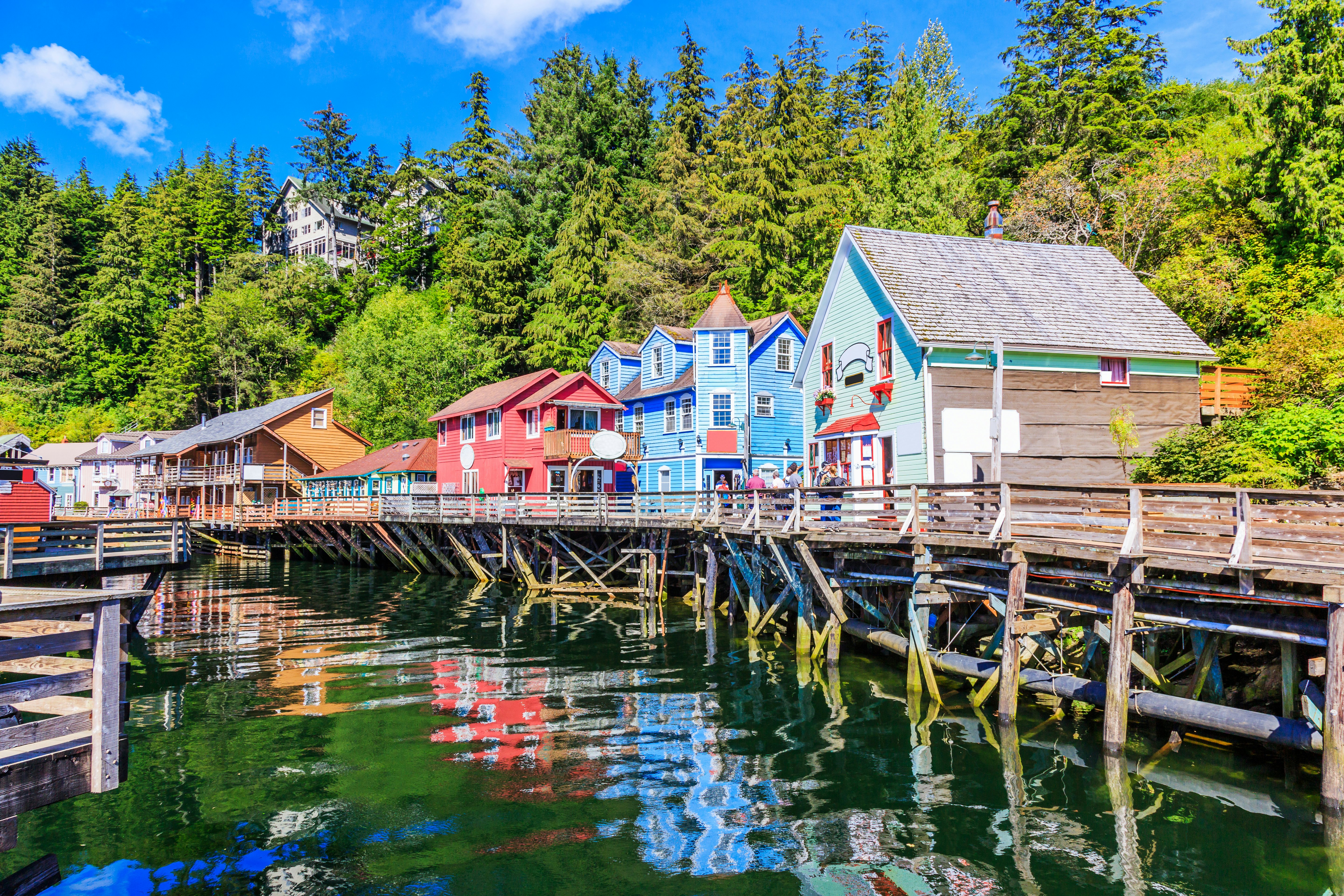 A colorful row of shop fronts raised on a pier above a small dock