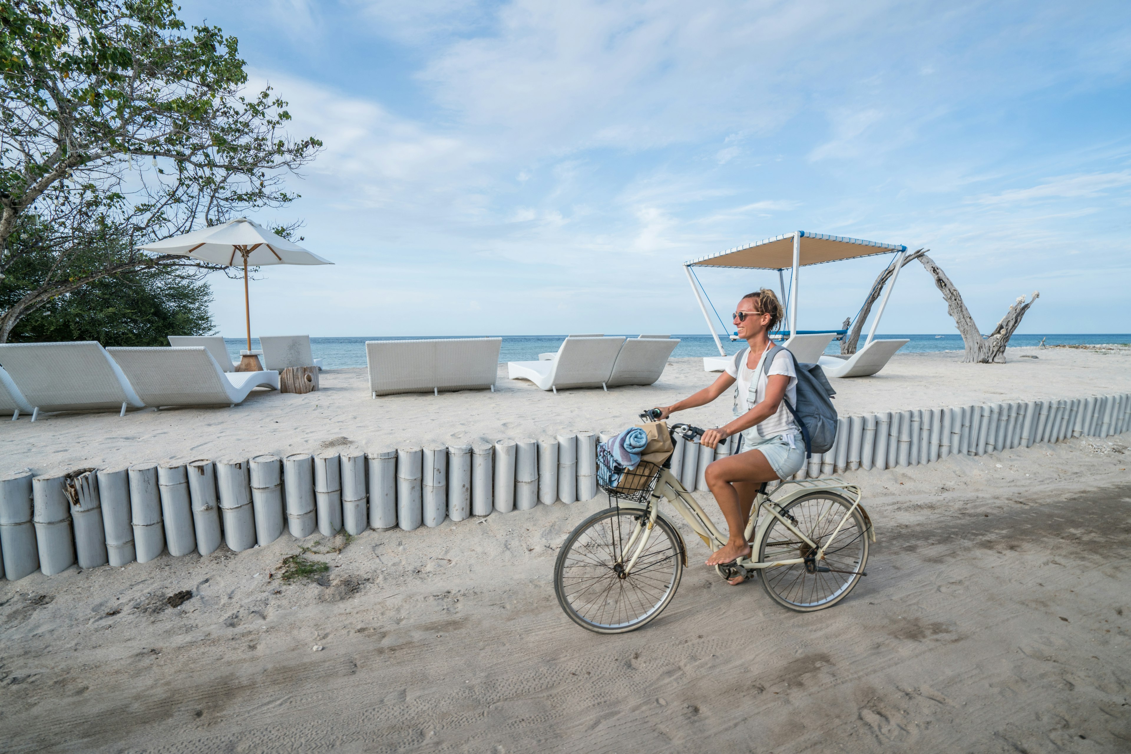 Smiling woman cycling on the beach during the morning.