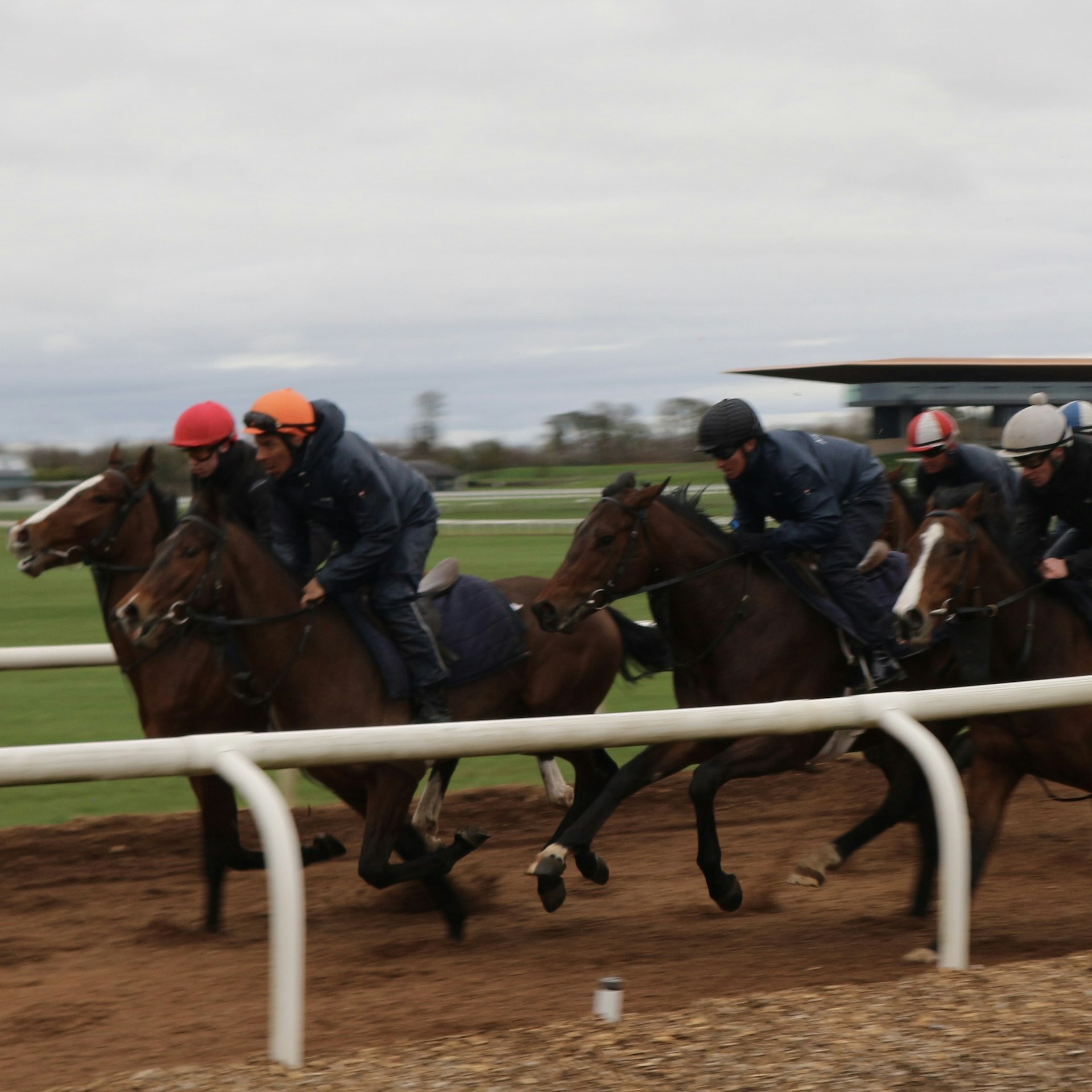 Horses on a race track being ridden by jockey in gloomy wet weather