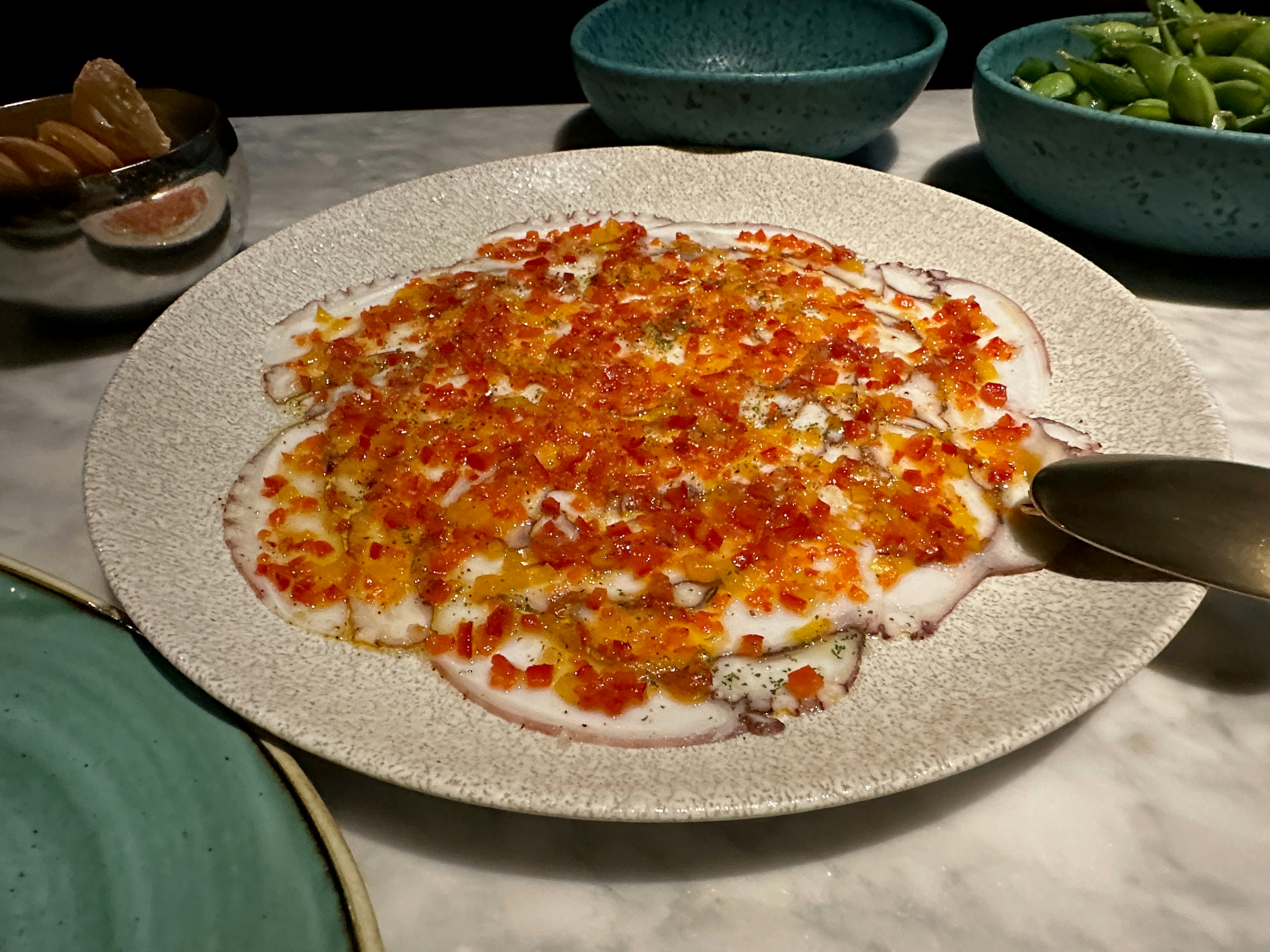 A flat wide dish filled with thin slices of octopus