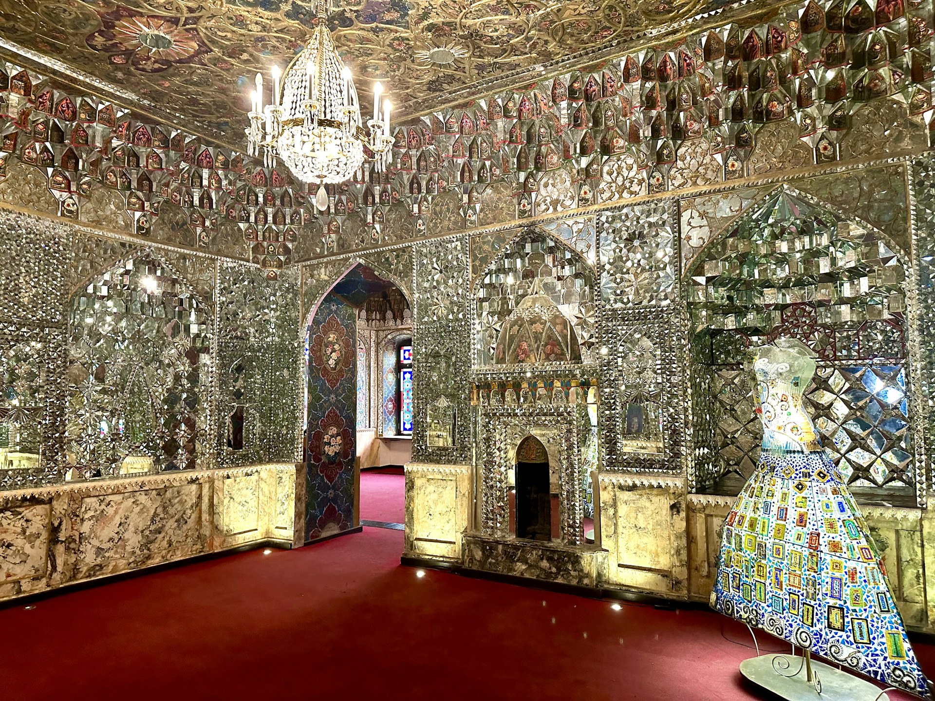 A red carpeted room with kaleidoscopic mirrors all over the walls. 