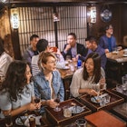 Wide angle view of Mongolian, Japanese, and Caucasian women sitting at sushi bar and other patrons in Tokyo izakaya.
1176105697