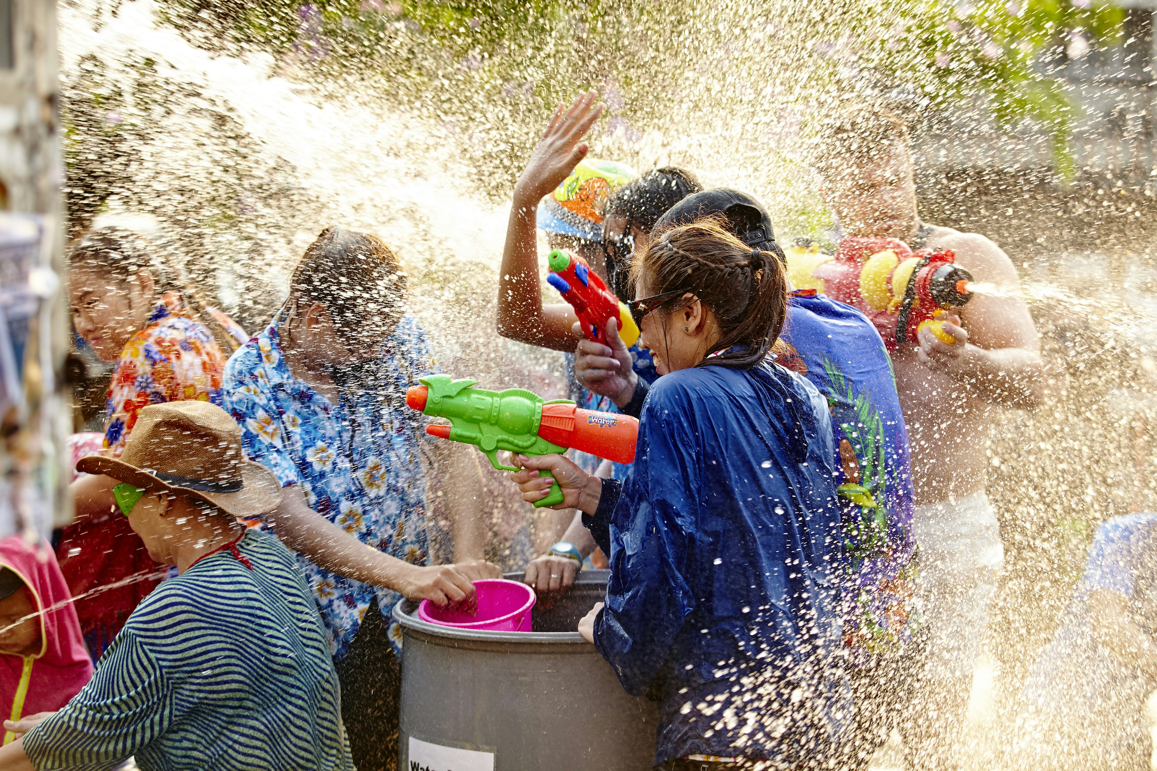 People in a huddle spraying and splashing each other with water as drops fly everywhere around them