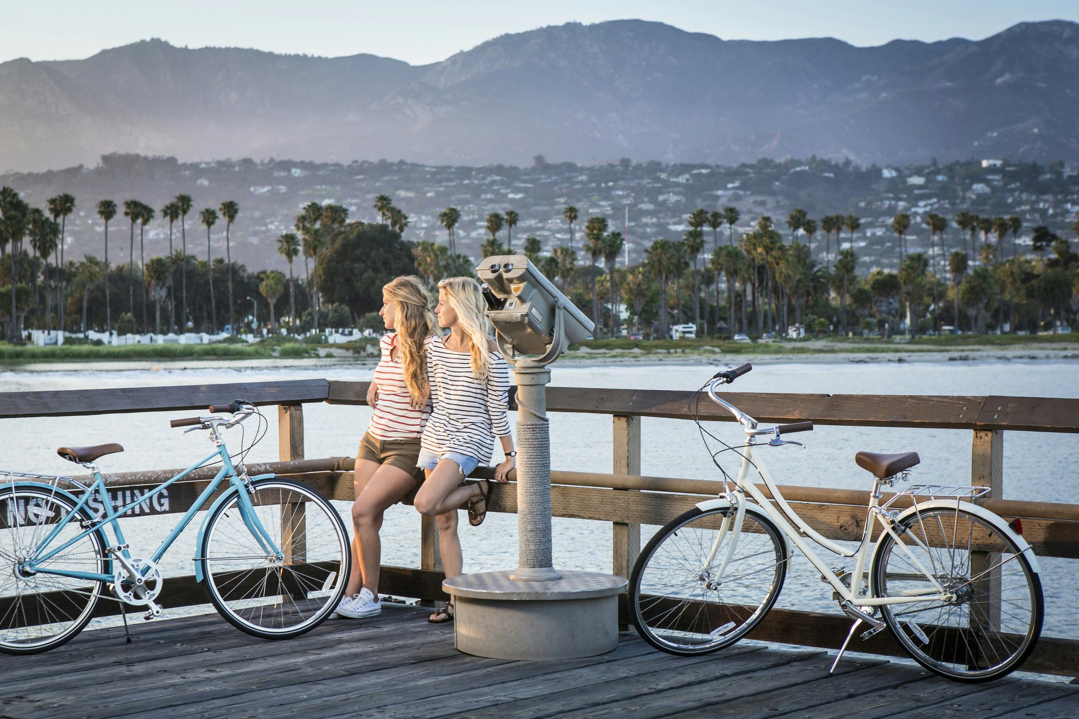 Two women with bikes on a pier in Santa Barbara at sunset