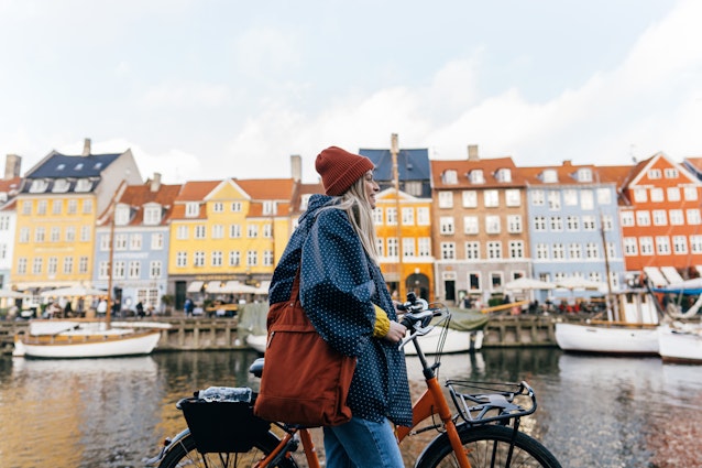 Photo of a young woman pulling the bike and walking down the street while exploring the famous tourist attraction in Copenhagen, Denmark.
1327471226