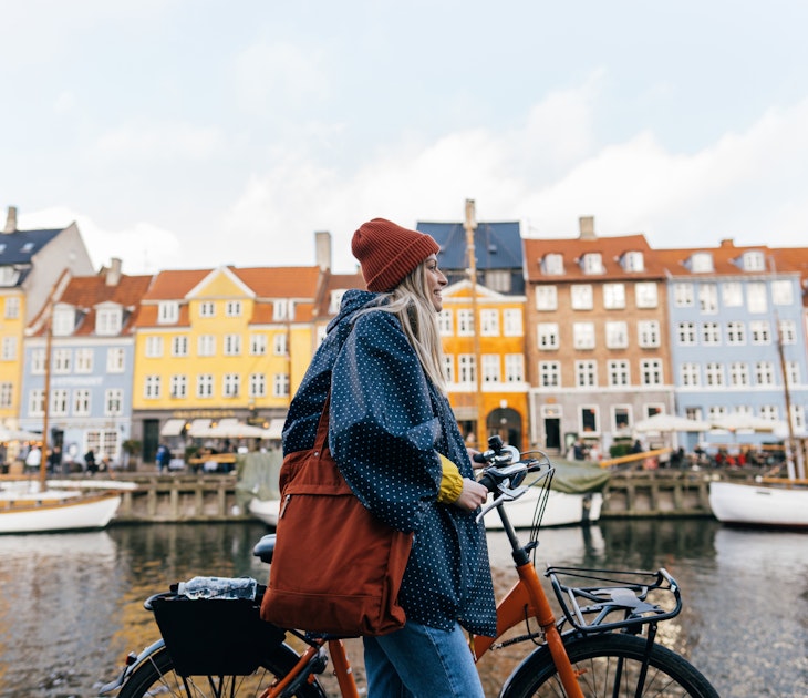 Photo of a young woman pulling the bike and walking down the street while exploring the famous tourist attraction in Copenhagen, Denmark.
1327471226