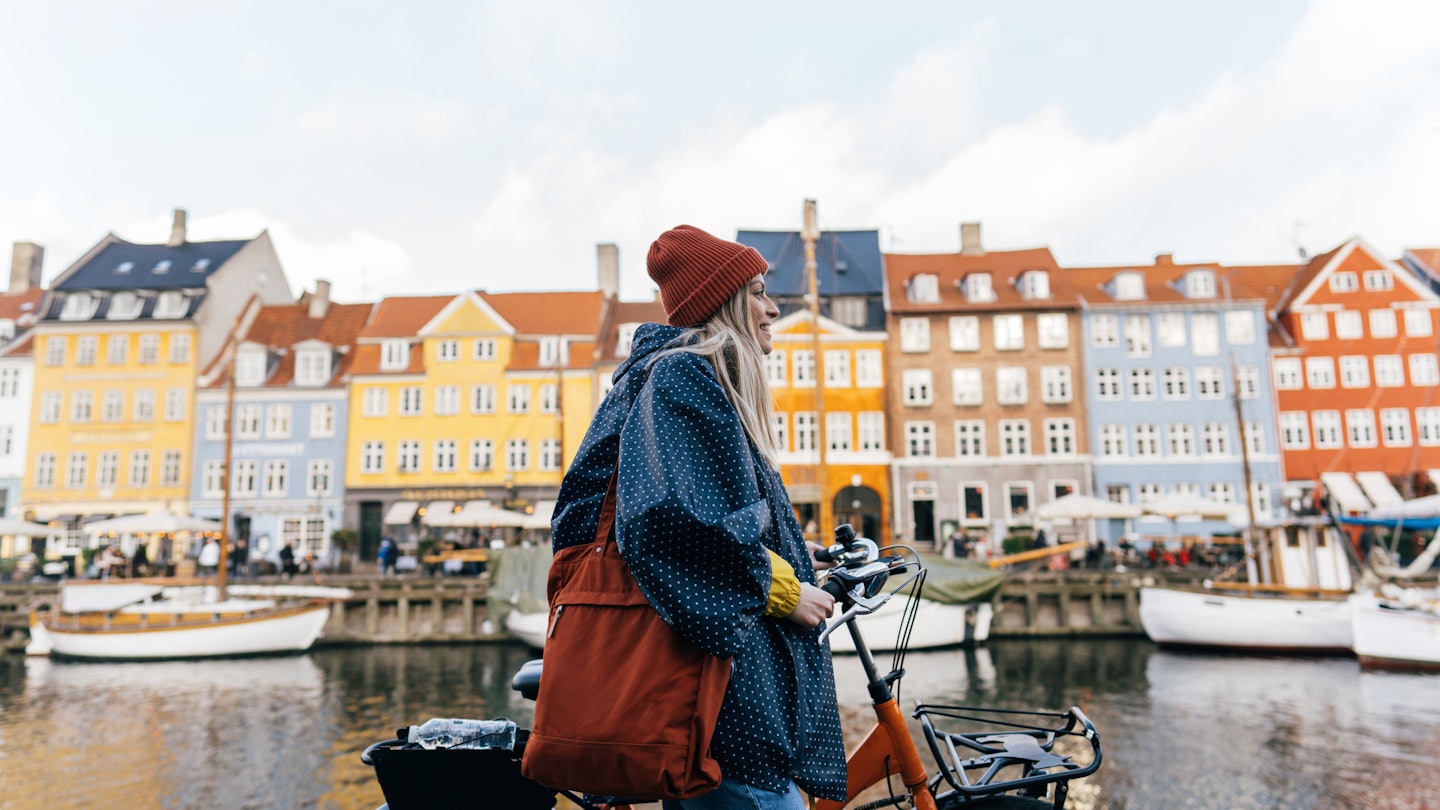 Photo of a young woman pulling the bike and walking down the street while exploring the famous tourist attraction in Copenhagen, Denmark.
1327471226