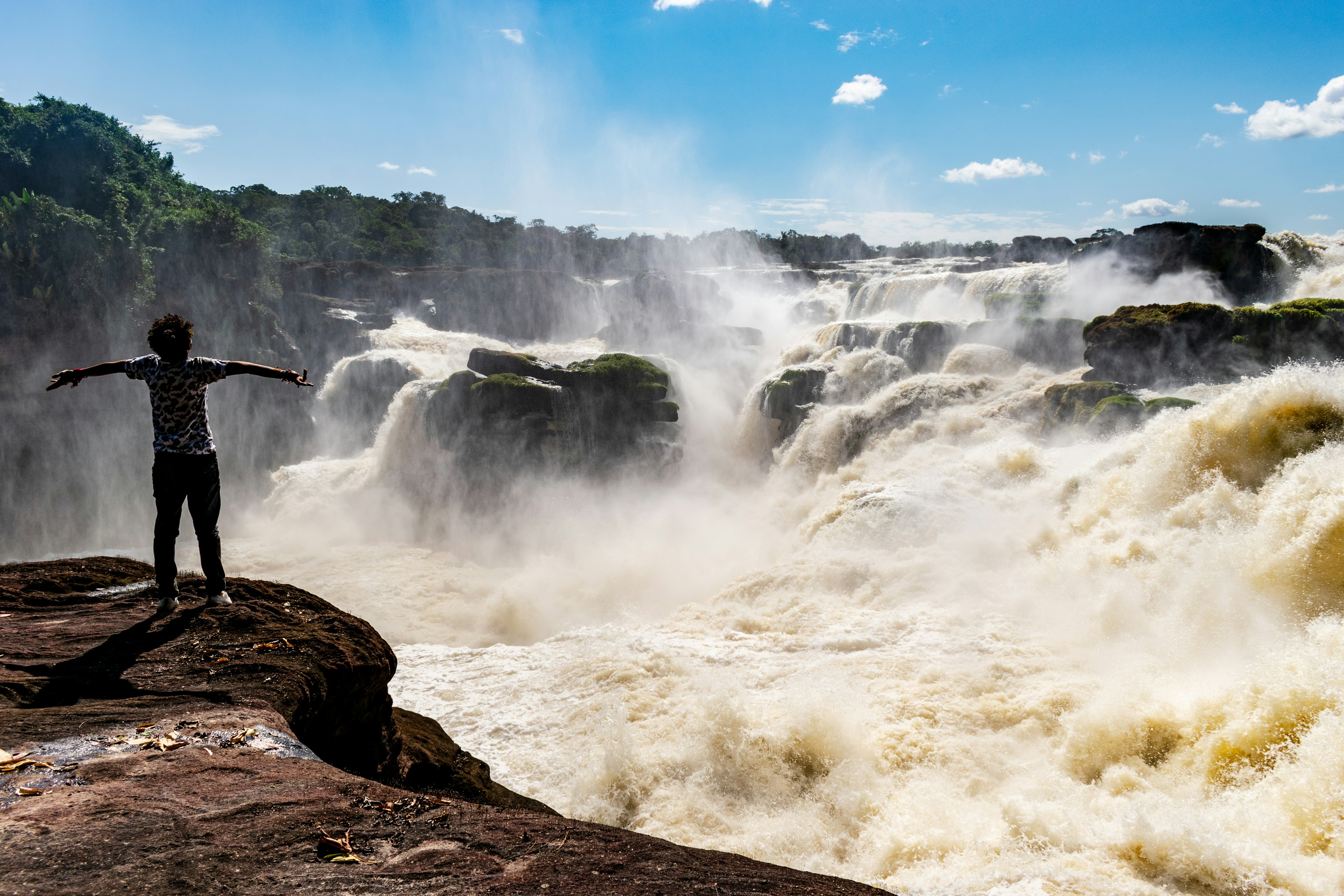 A person stands in front of the roaring waterfalls of Raudal de Jirijirimo