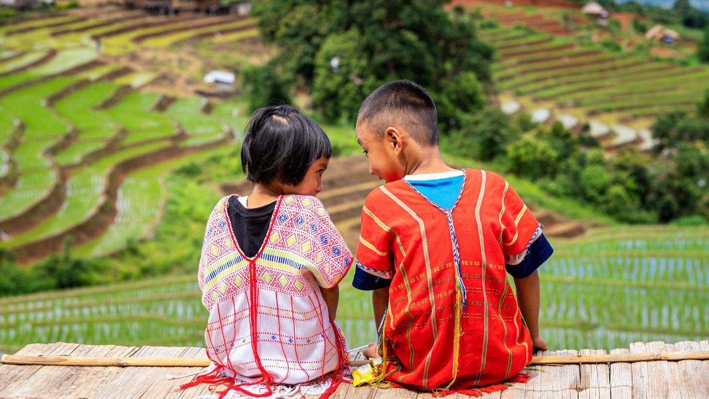 A boy and a girl dressed in hill tribe clothing are sitting on the terraced rice fields. ; Shutterstock ID 1997029631; GL: 65050; netsuite: Online ed; full: Chiang Mai with kids; name: Claire N
1997029631