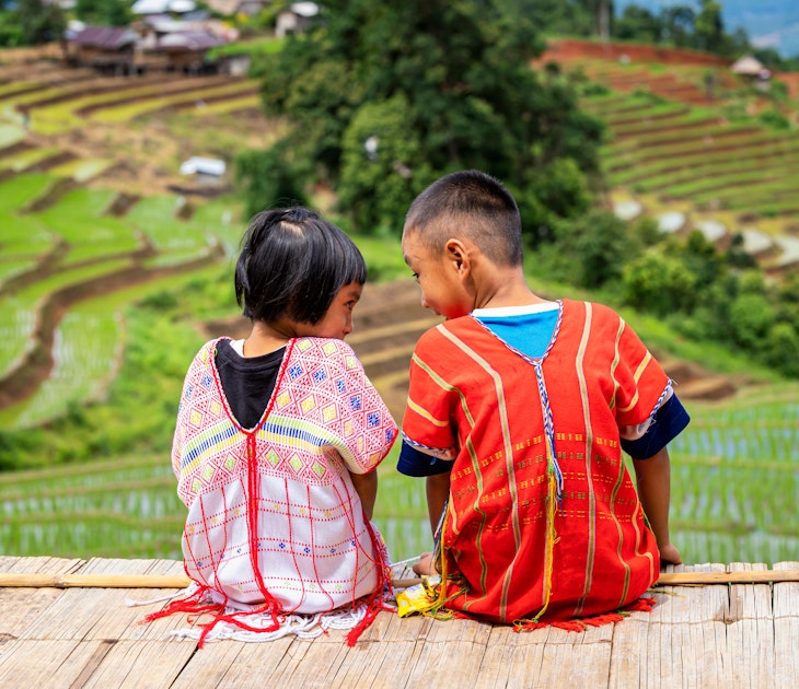 A boy and a girl dressed in hill tribe clothing are sitting on the terraced rice fields. ; Shutterstock ID 1997029631; GL: 65050; netsuite: Online ed; full: Chiang Mai with kids; name: Claire N
1997029631