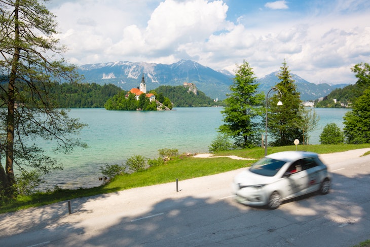 Motion blured white electric car in front of Bled lake, country of Slovenia. Travel, tourism, explore, rent a car concept.; Shutterstock ID 1999753226; GL: 65050; netsuite: Online ed; full: Slovenia transportation; name: Claire N
1999753226