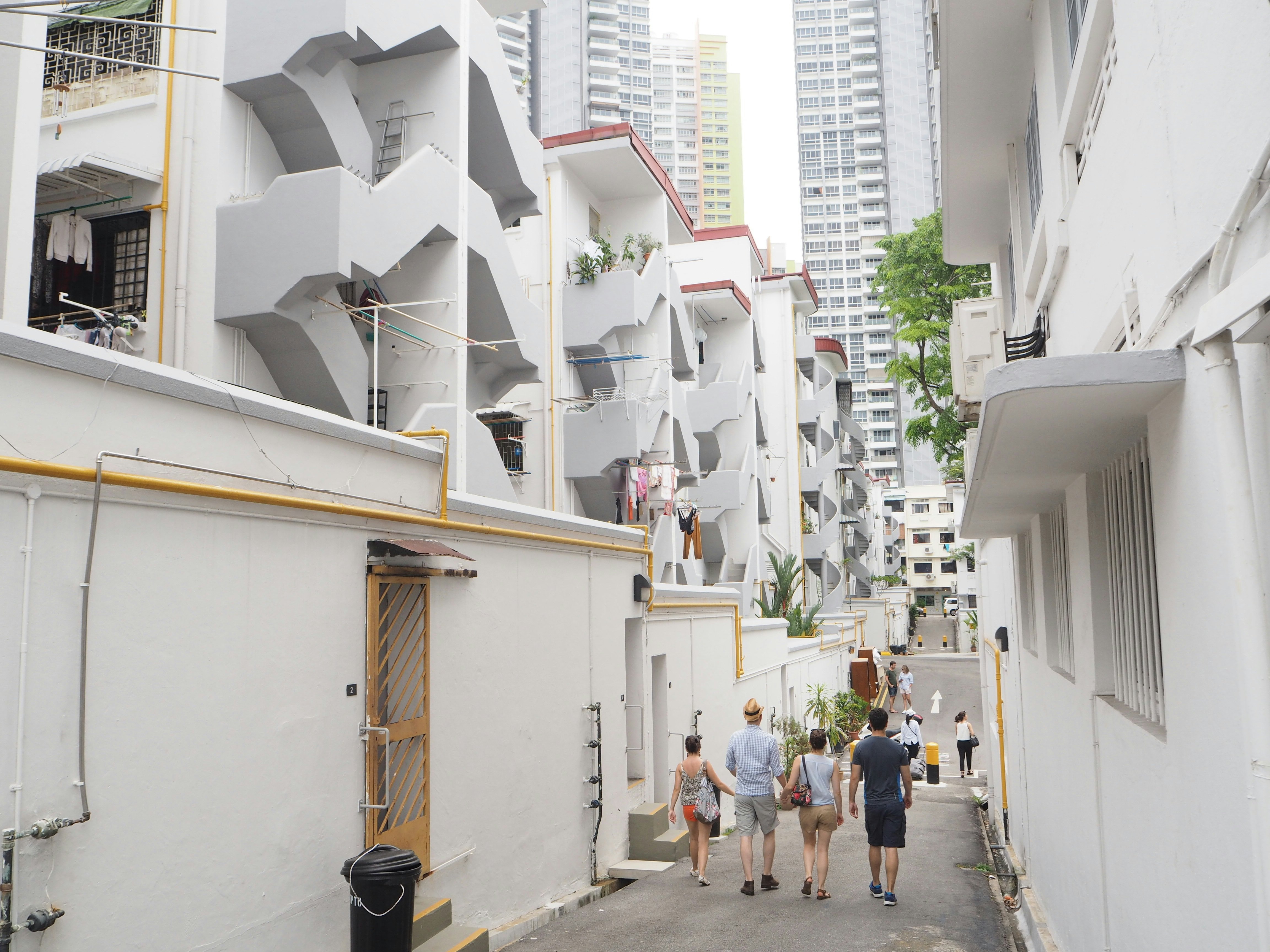 People walk between large white buildings in Tiong Bahru