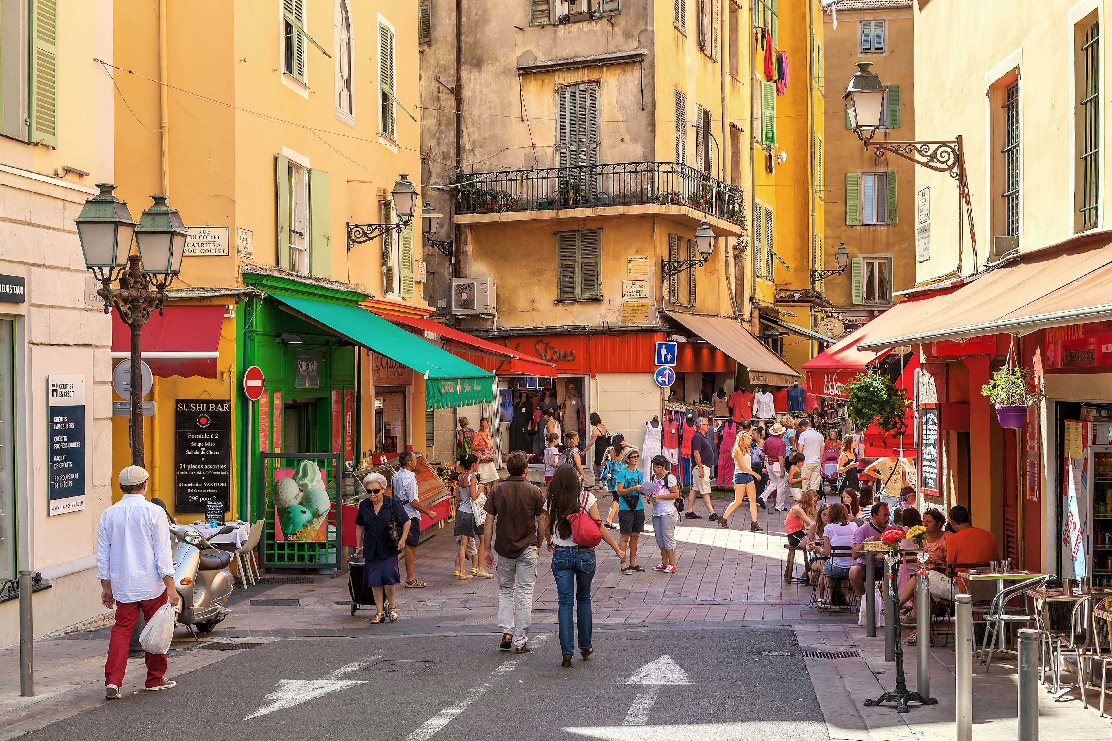 People walking through an old town in a city with small boutiques and cafes