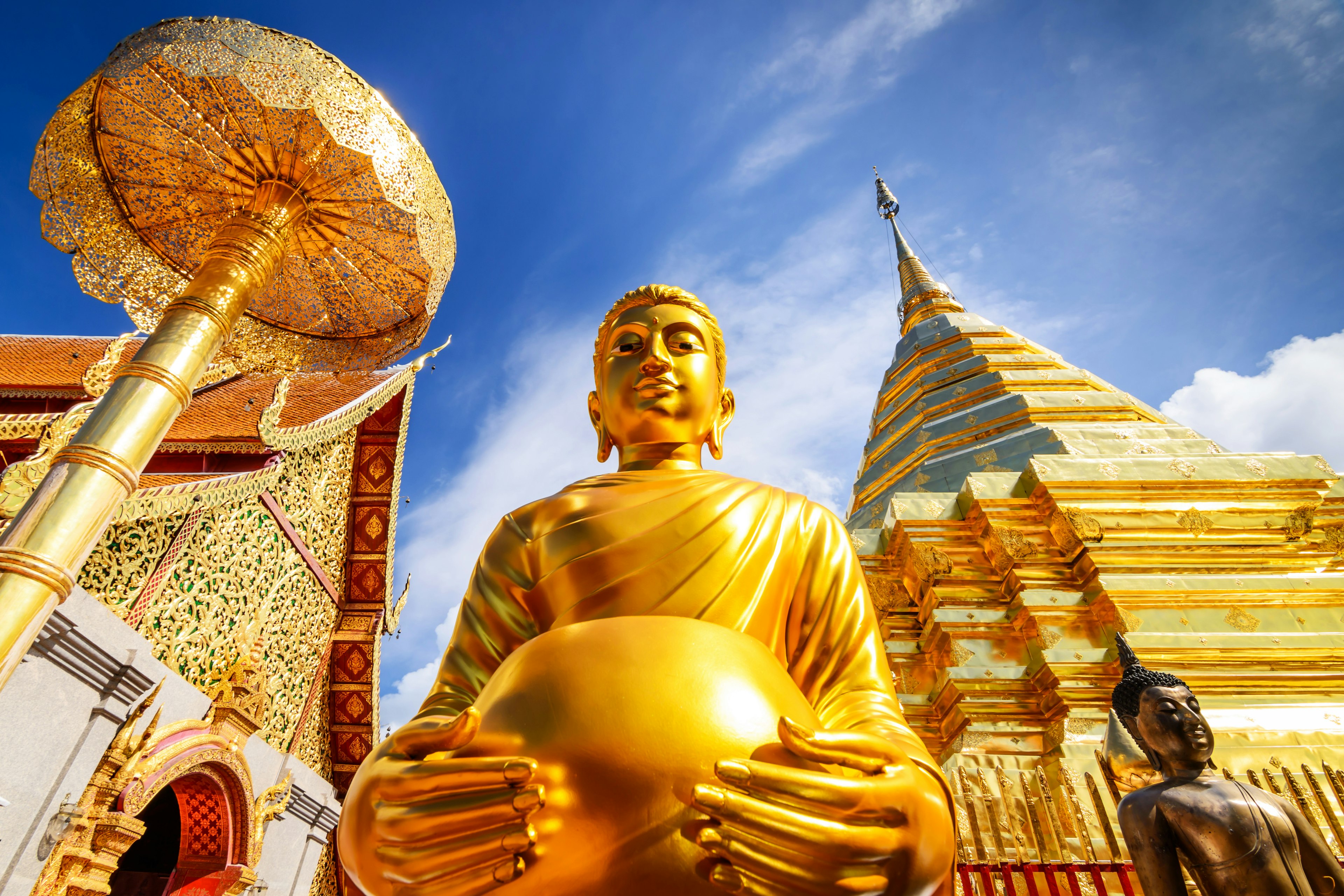 A large gold buddha statue within a temple complex