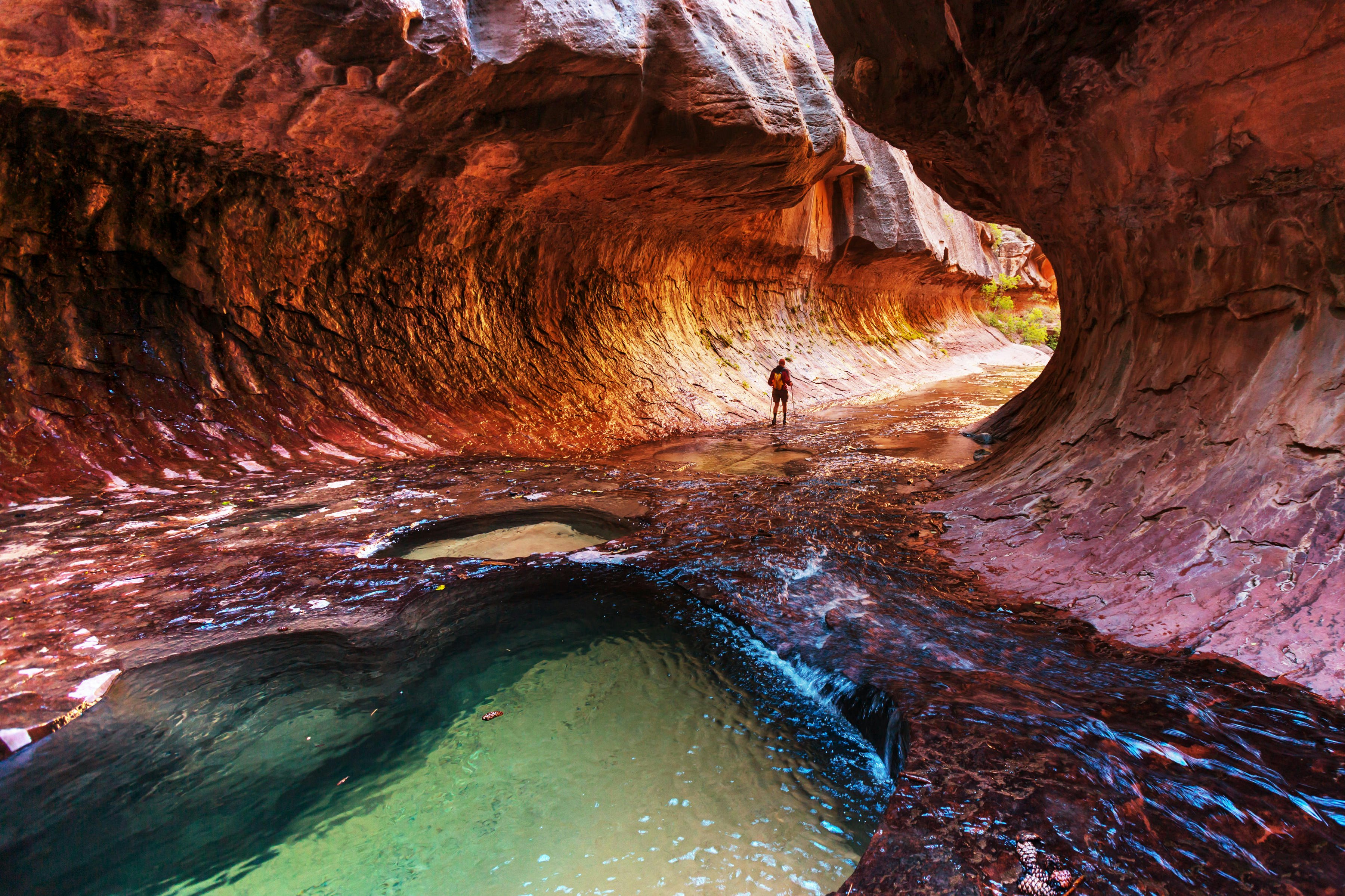 A hiker walks through the Narrows gorge in Zion National Park.