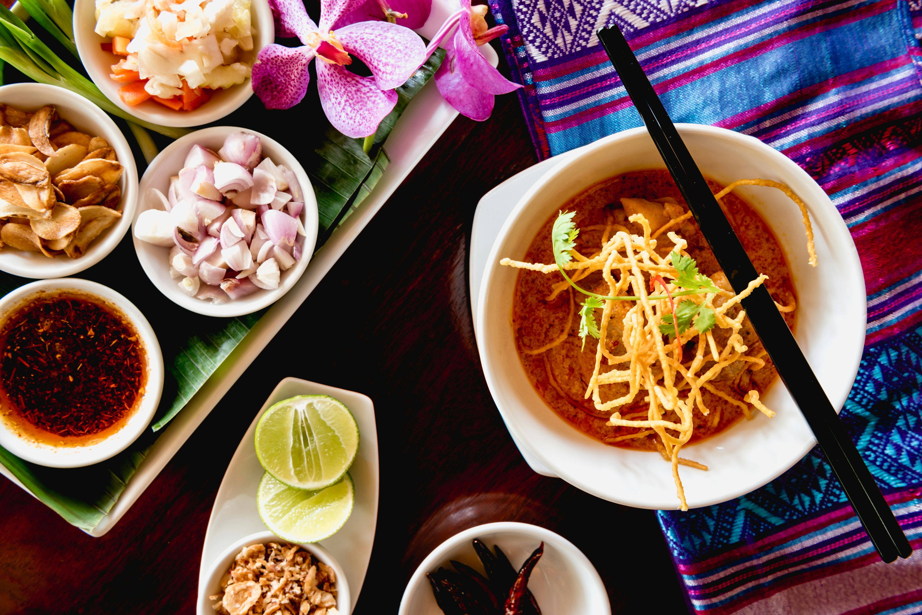 A shot of a dish with a coconut-curry sauce and crispy noodles