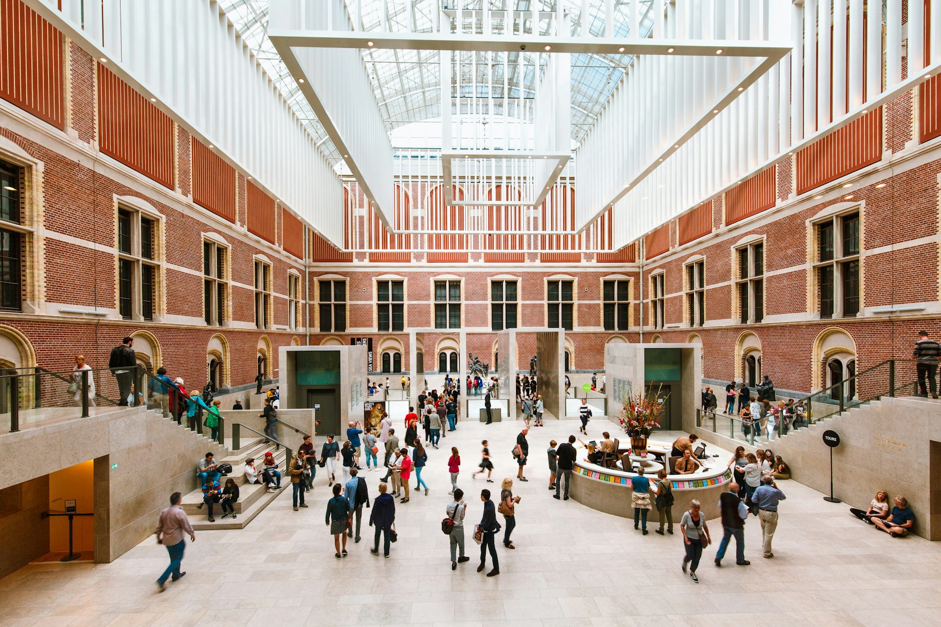 Visitors in modern main hall in the new atrium of the Rijksmuseum. Entrance to museum, massive ceiling decorations and people in dutch national museum.
