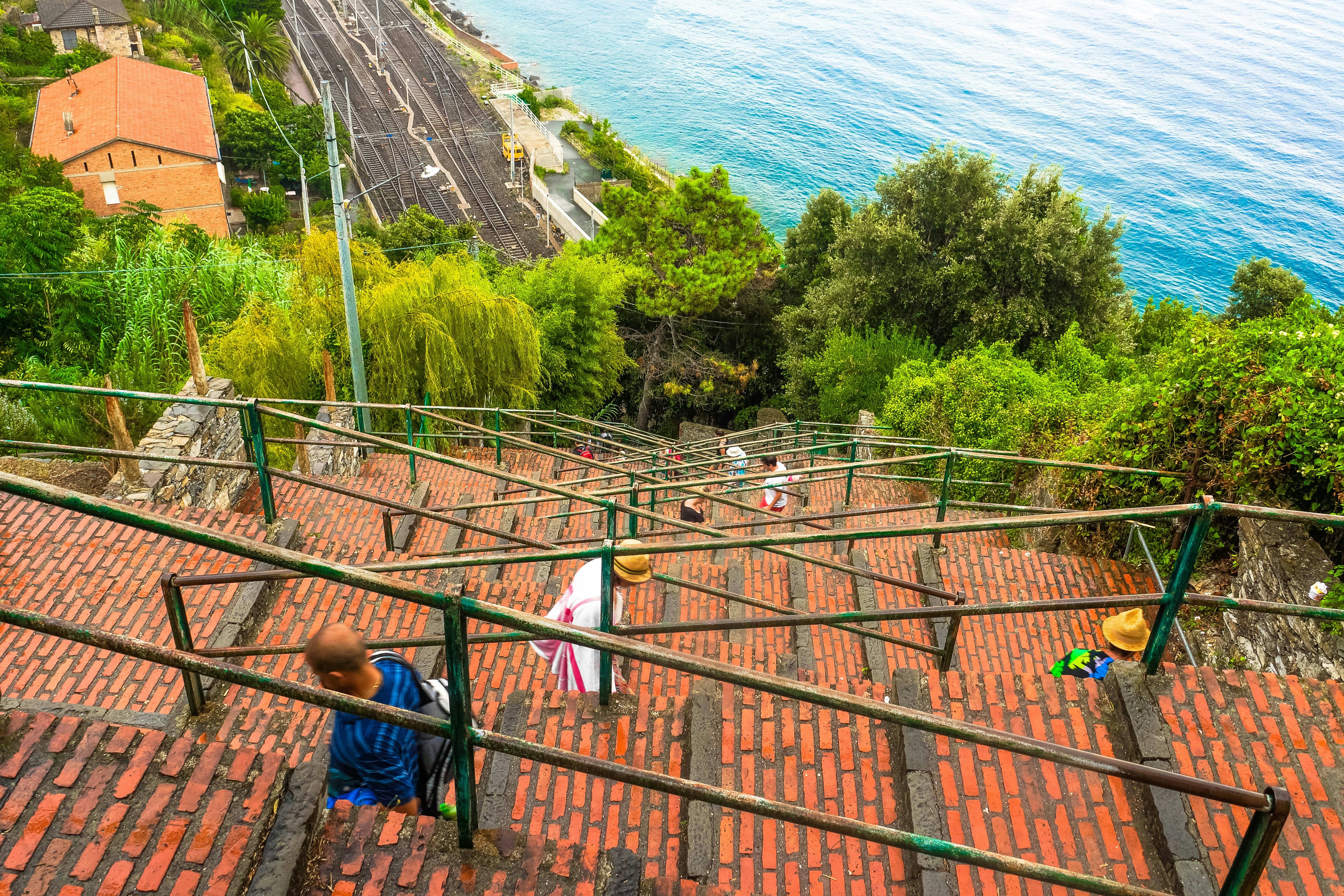 A long brick flight of steps with handrails zig zags down to a coastal train station