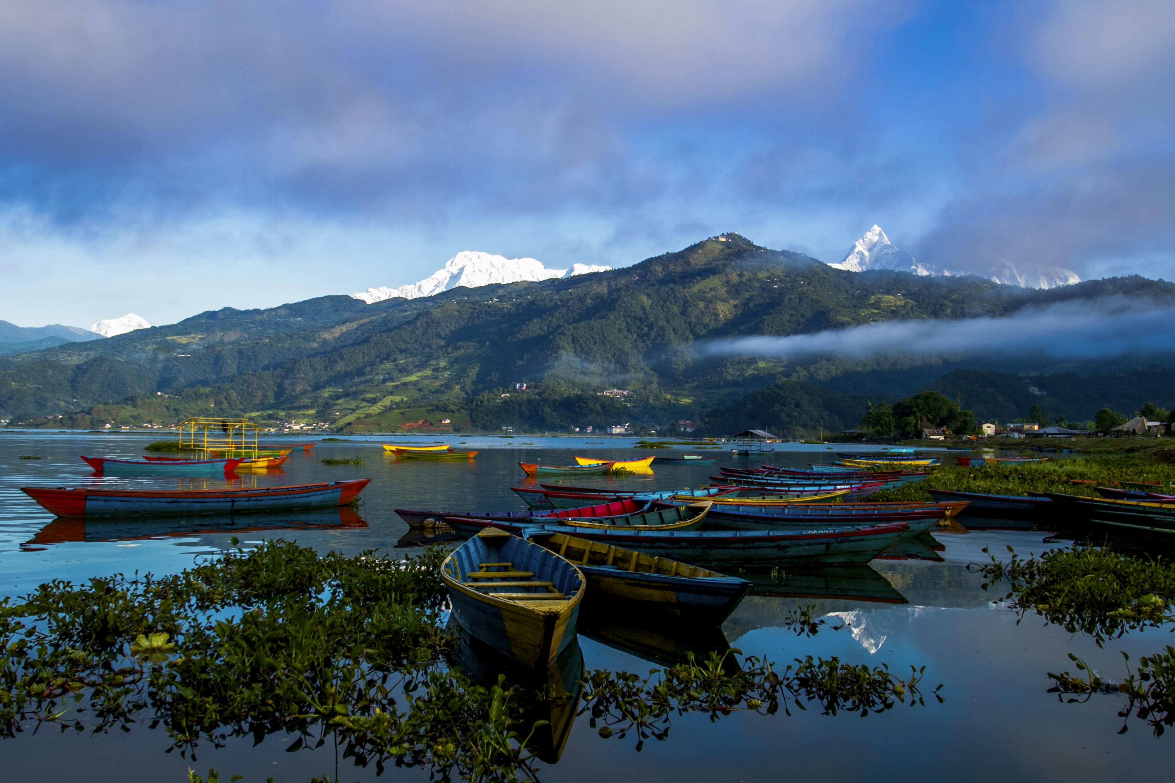 Small wooden boats float at the edge of a lake