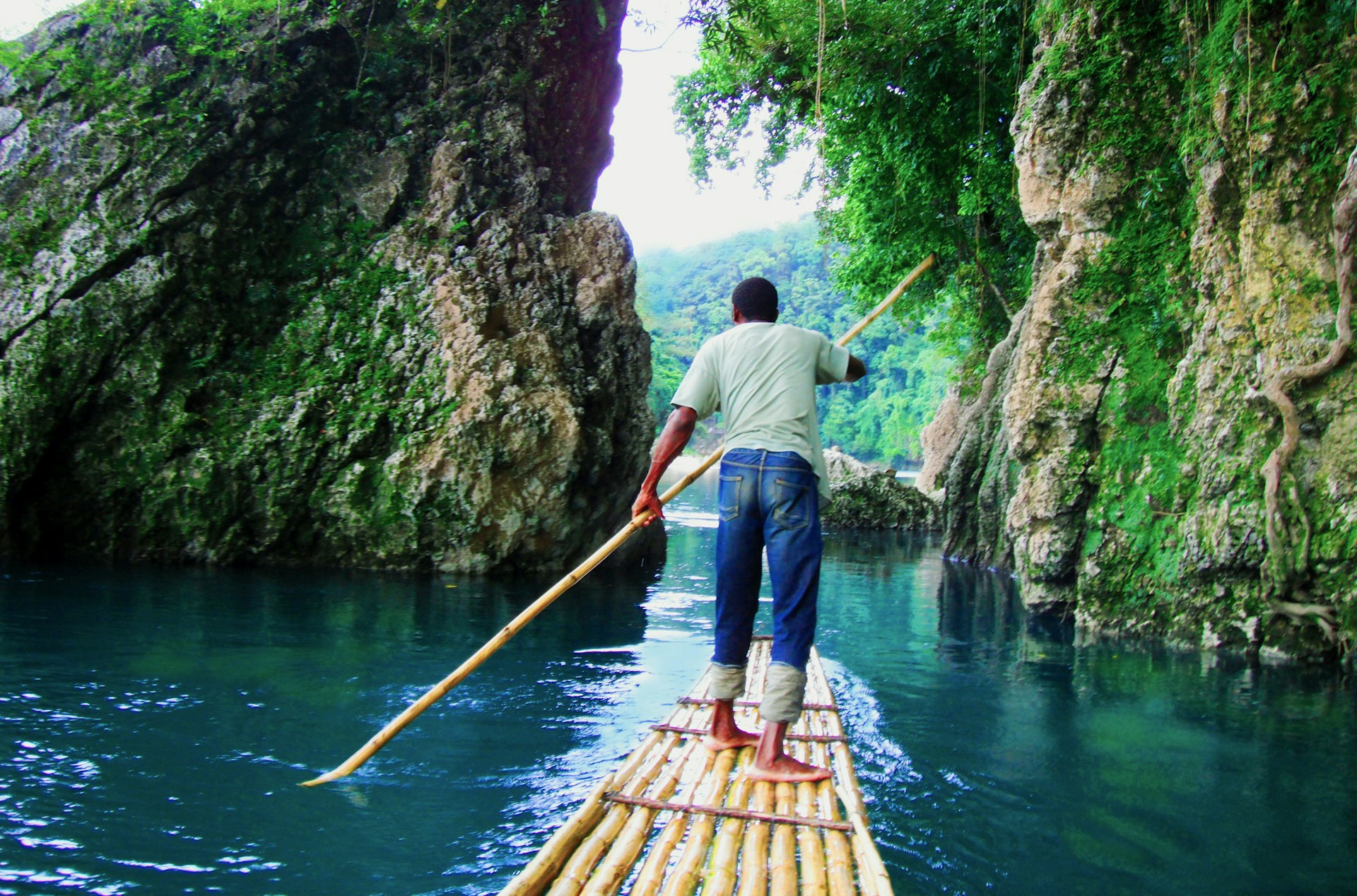 A man paddles along a river on a bamboo raft