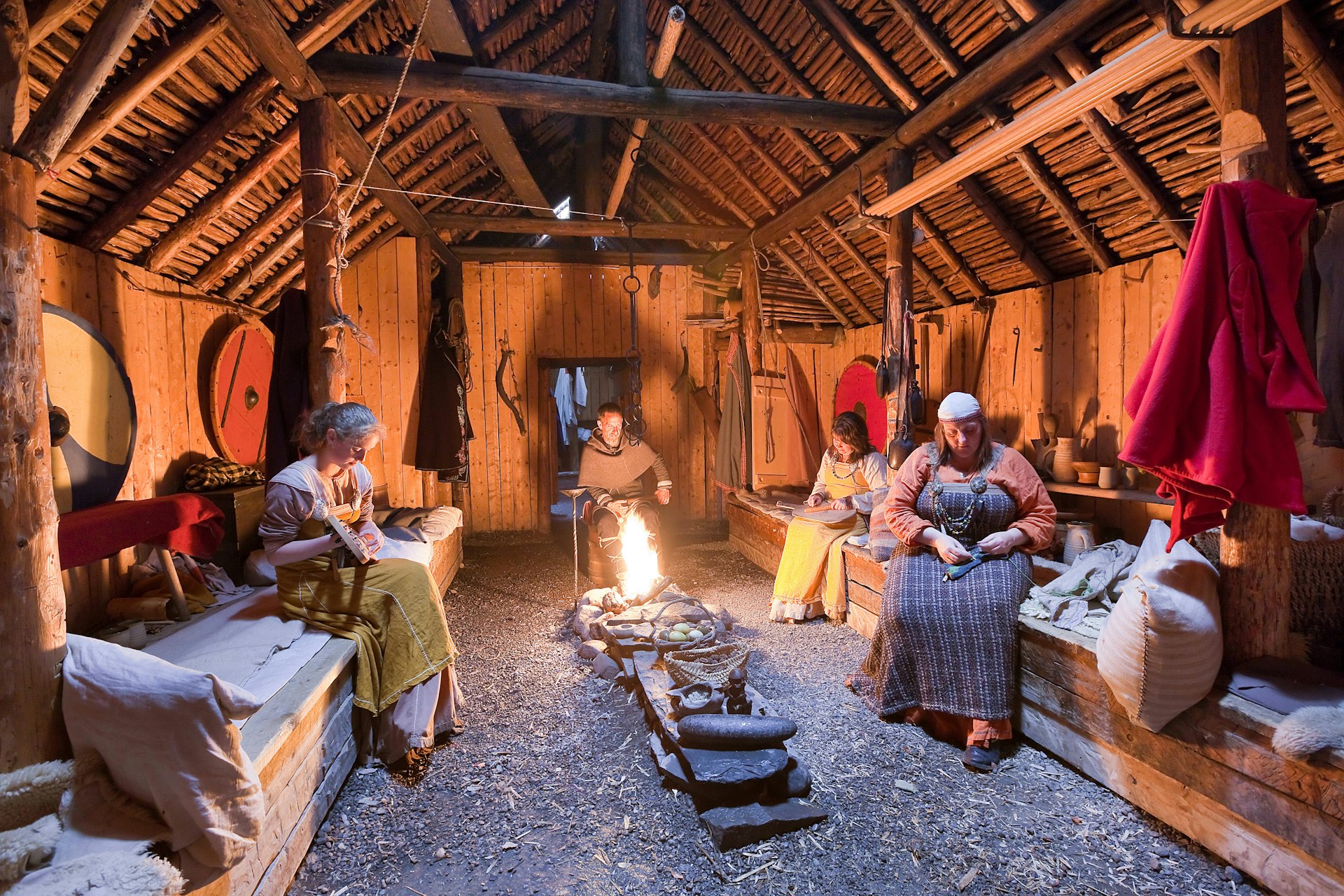 Parks Canada interpreters in period costumes performing traditional tasks inside a recreated Viking longhouse at L’Anse aux Meadows National Historic Site, Newfoundland, Canada