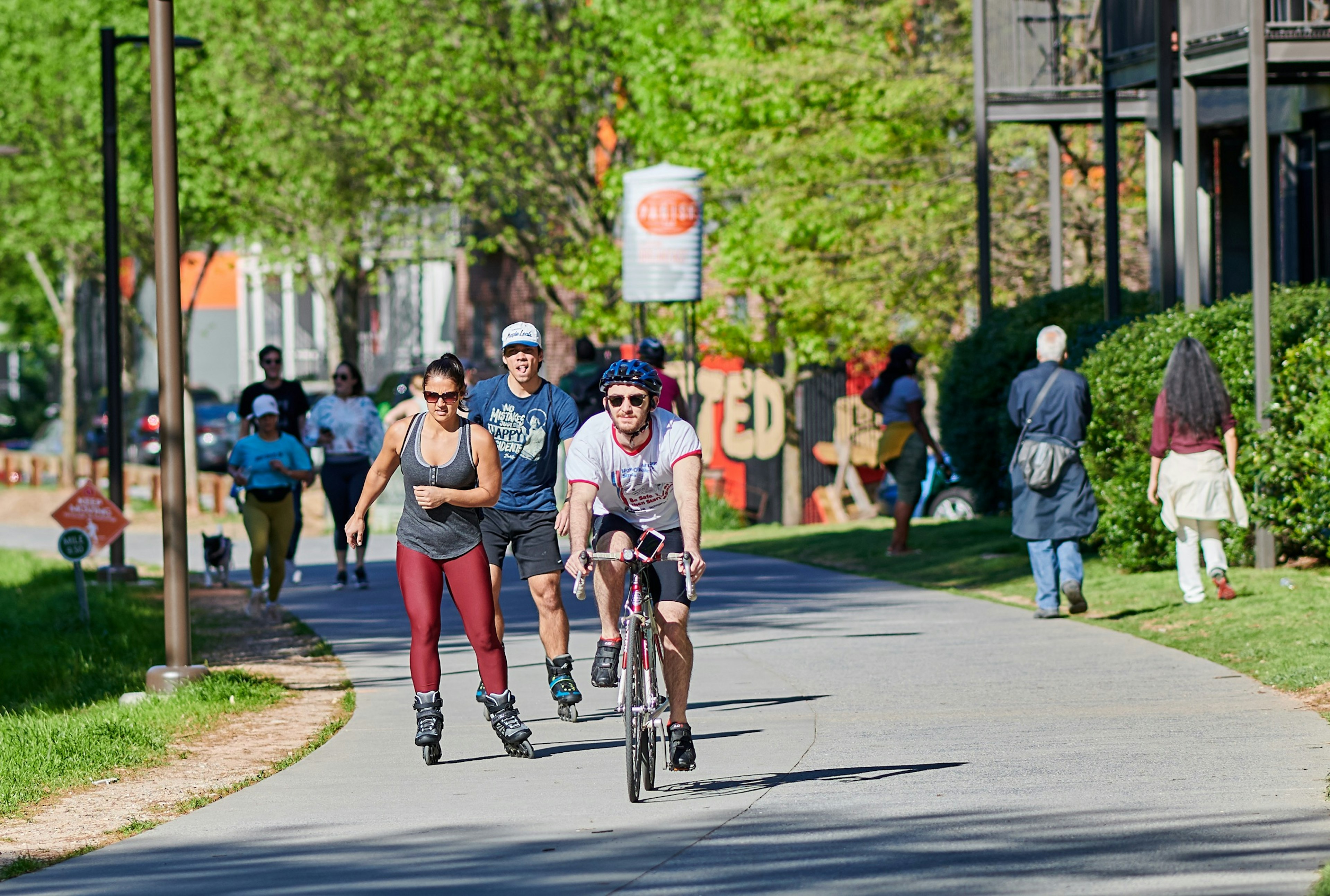 A group of people bike, roller blade and walk down the paved Atlanta Beltline.