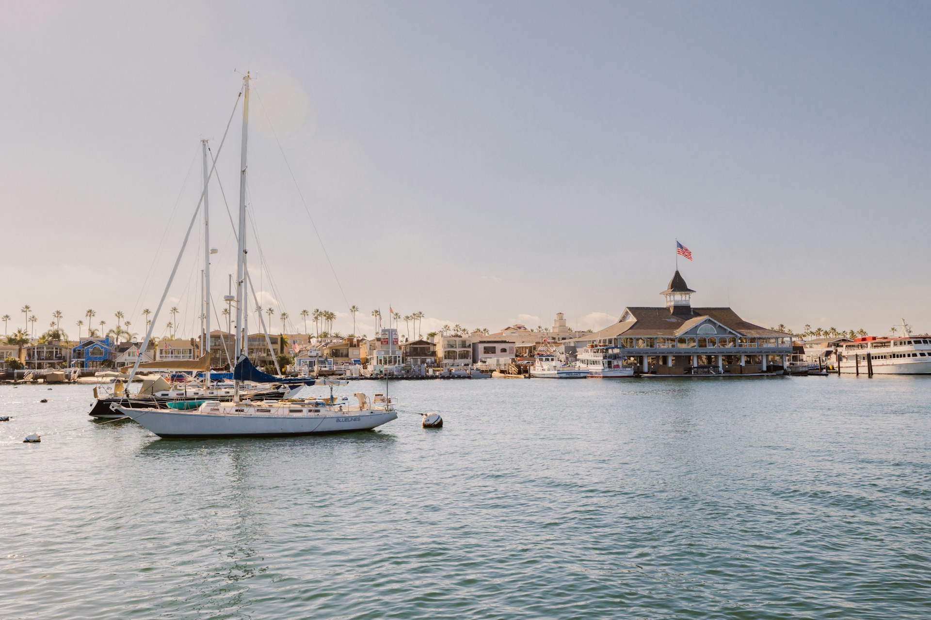 Newport Harbor with sailboats in the foreground and Balboa Pavillion in the background