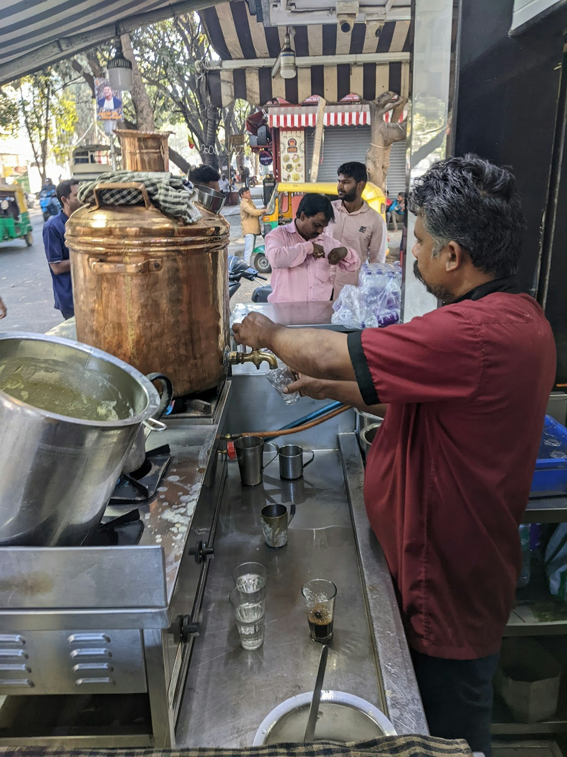 A man prepares coffee at a large urn out on the street