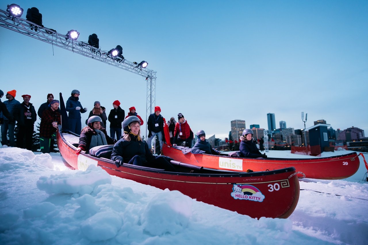 A group gets ready to race down a snowy hill as part of the Flying Canoe Volant