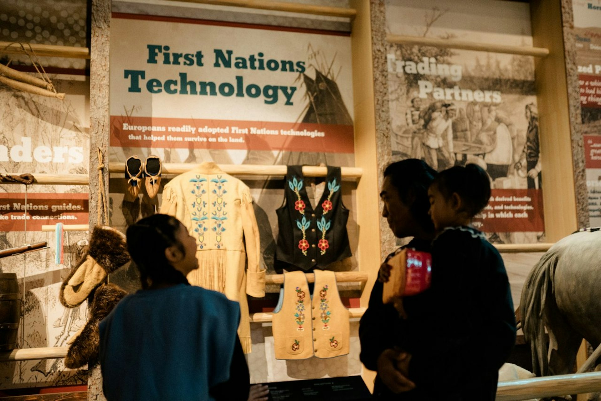 A family looks at an exhibit about Indigenous technology at Fort Edmonton Park