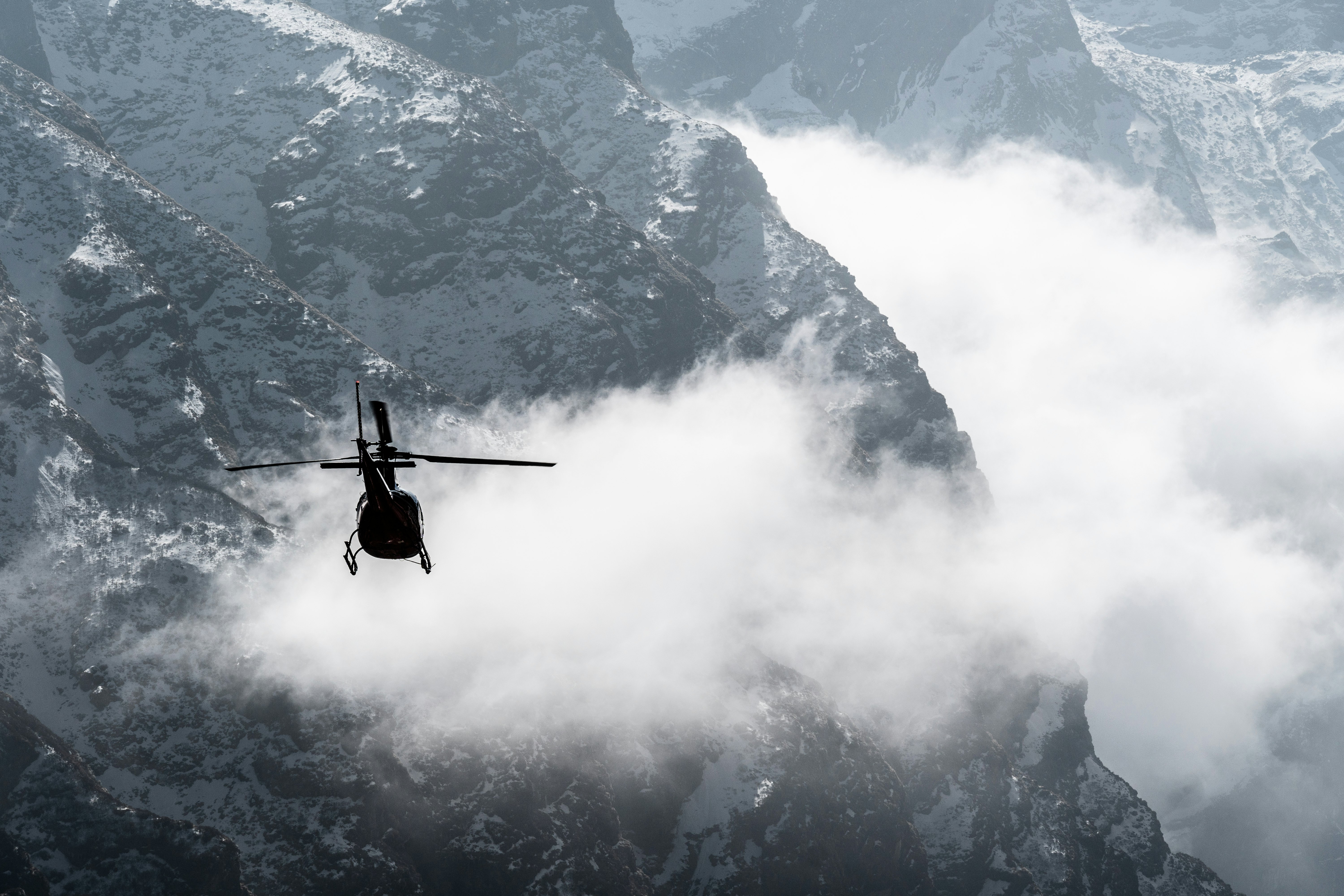 A helicopter flies among low clouds above the Annapurna Himalayas, Nepal