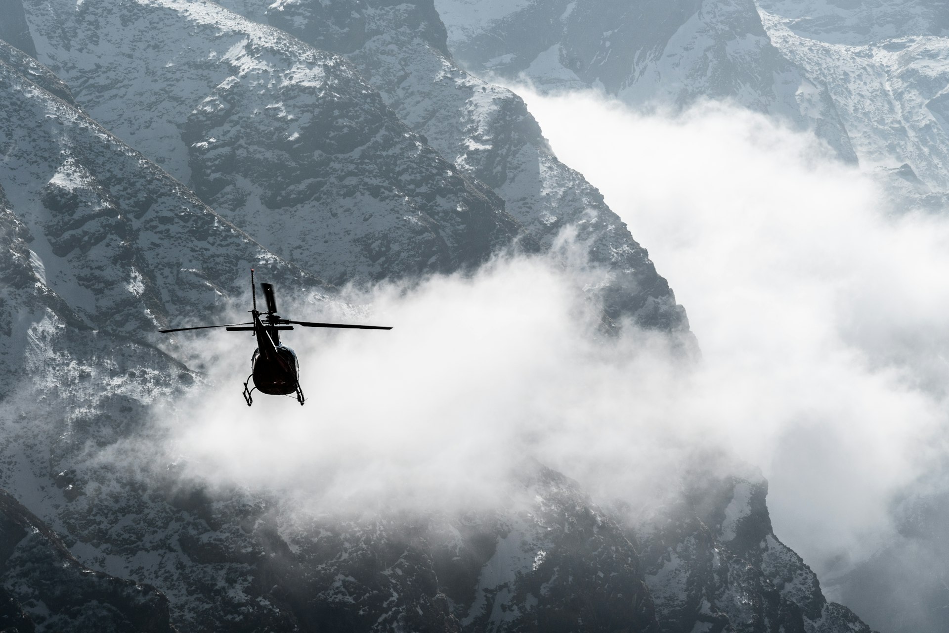 A helicopter flies among low clouds above the Annapurna Himalayas, Nepal