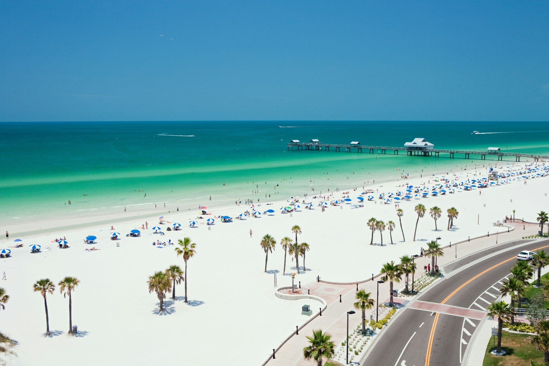 An aerial view of people on a white sand beach with turquoise water at Florida's Clearwater Beach