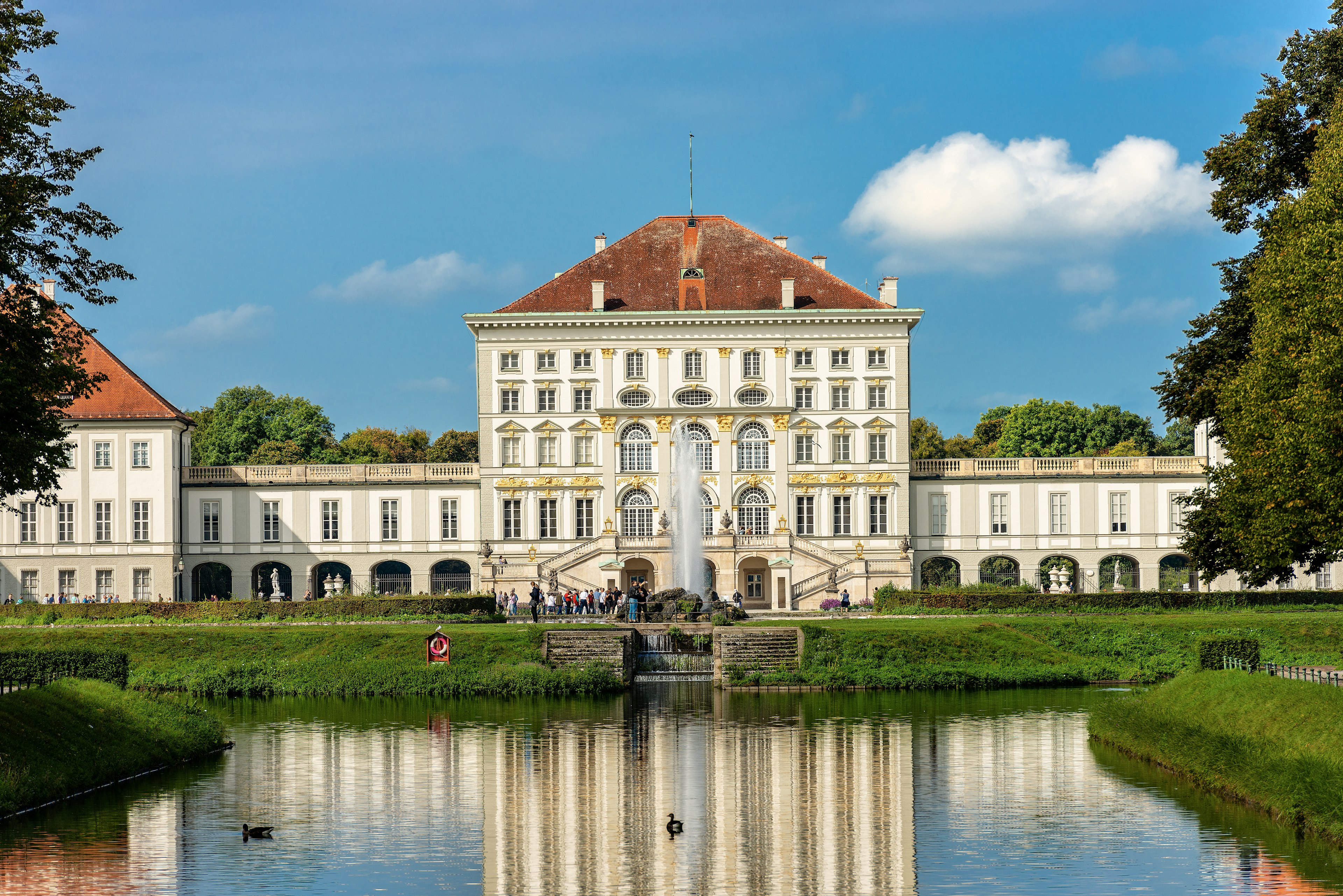 The exterior of a vast palace with people moving around on its terraces