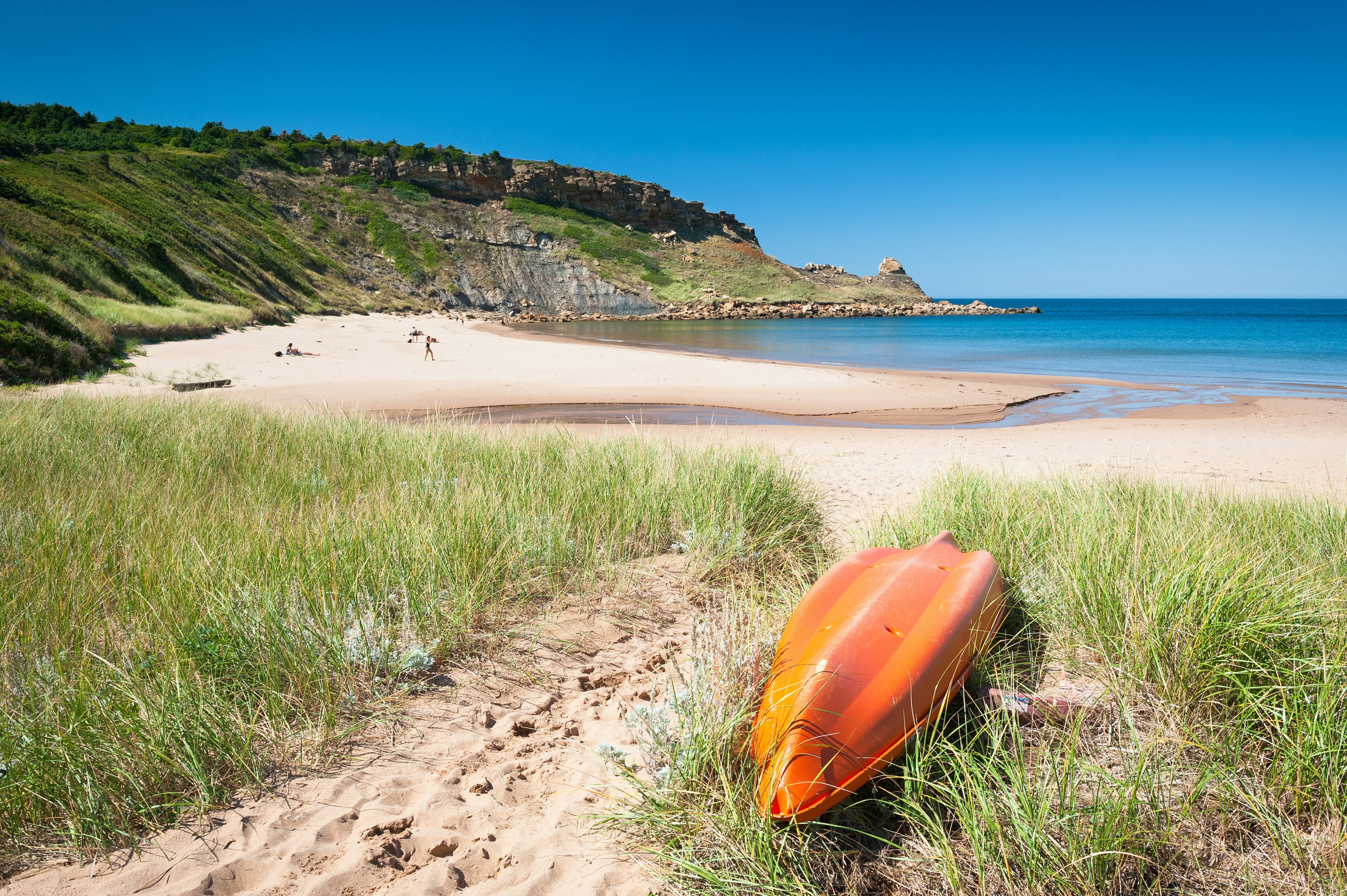 A kayak sits in the grass next to Chimney Corner Beach, Cape Breton, Nova Scotia