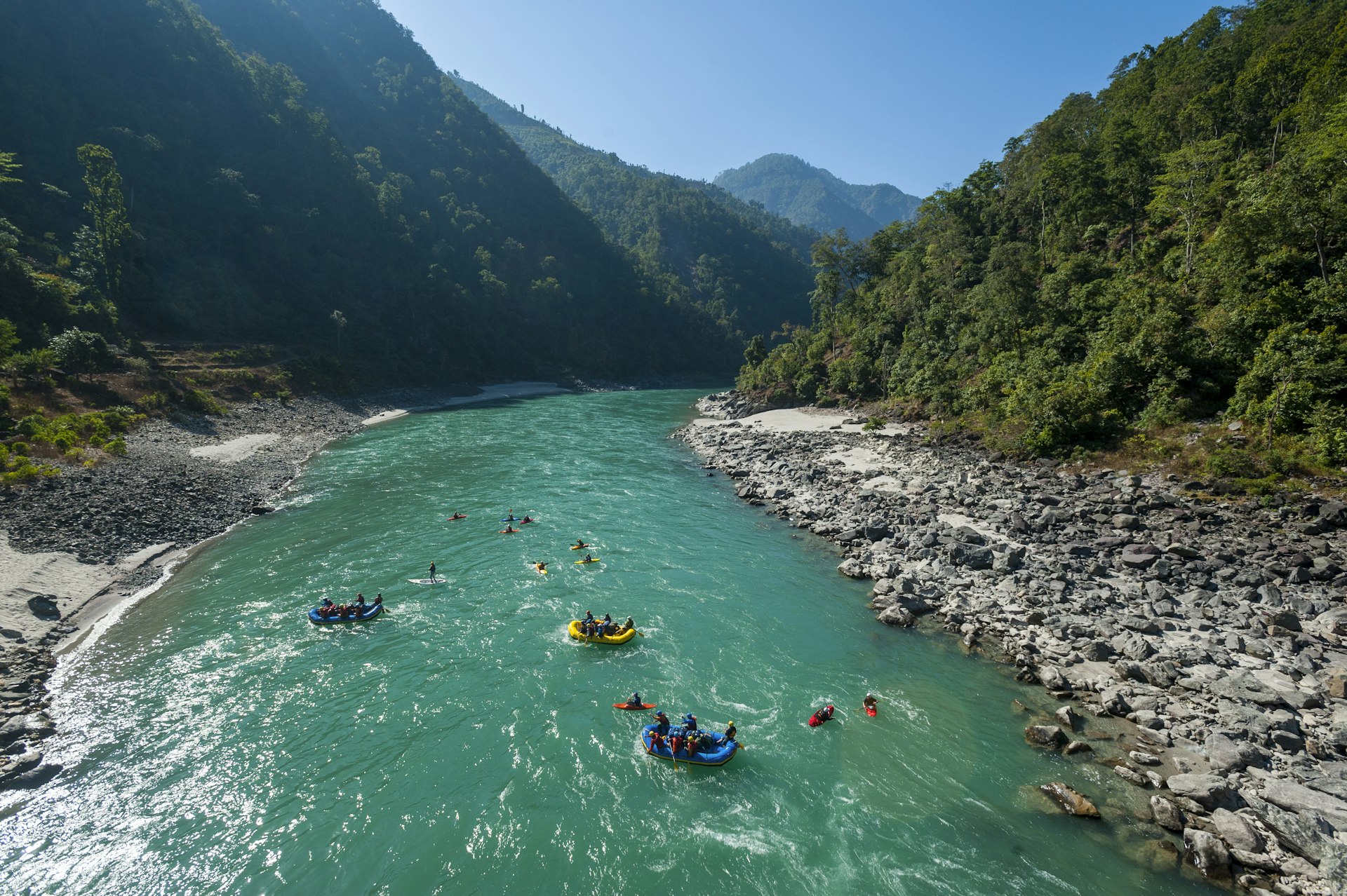 Rafts and kayaks drift down the Karnali river in Nepal 