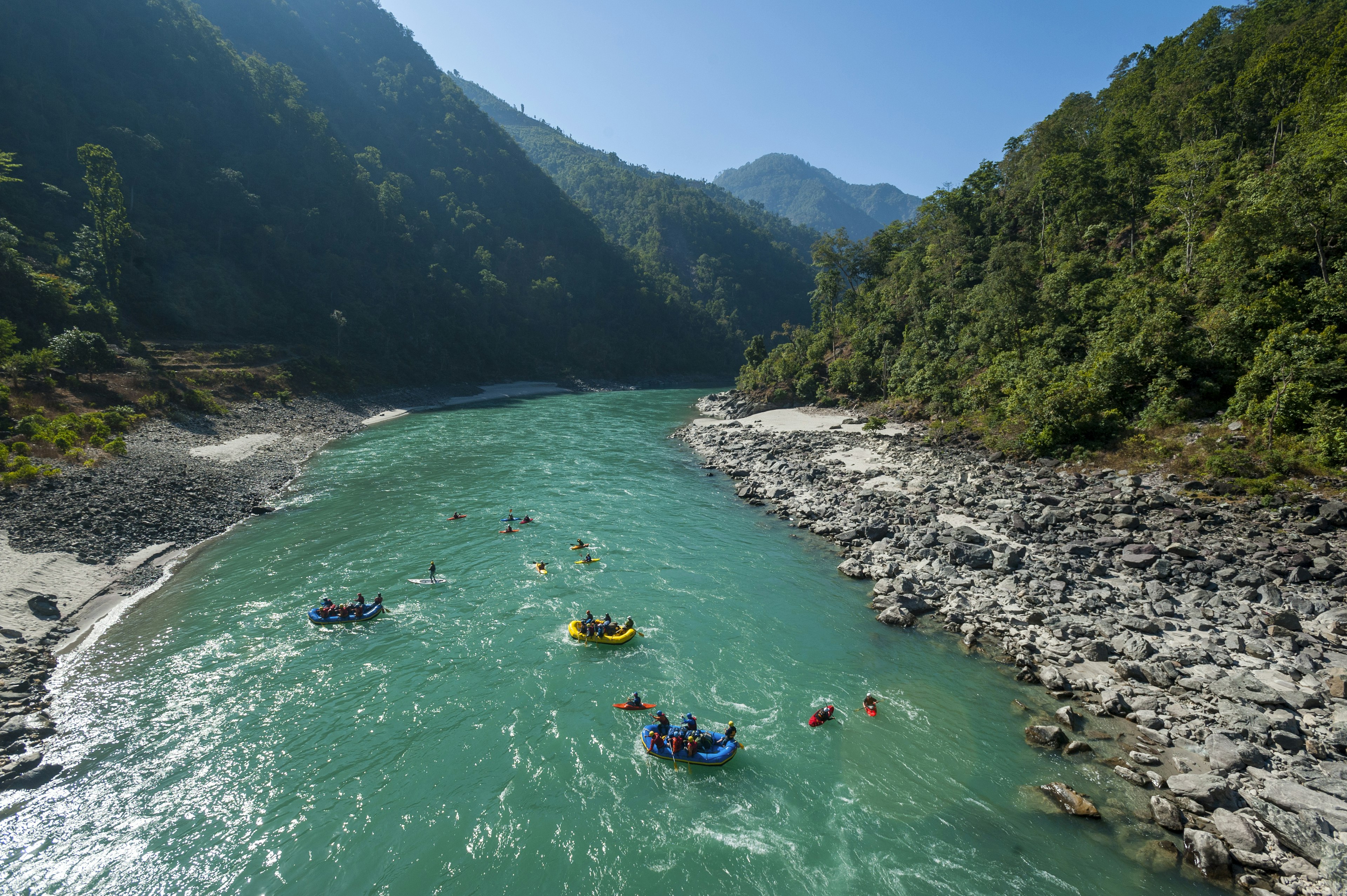 Rafts and kayaks drift down the Karnali river in Nepal