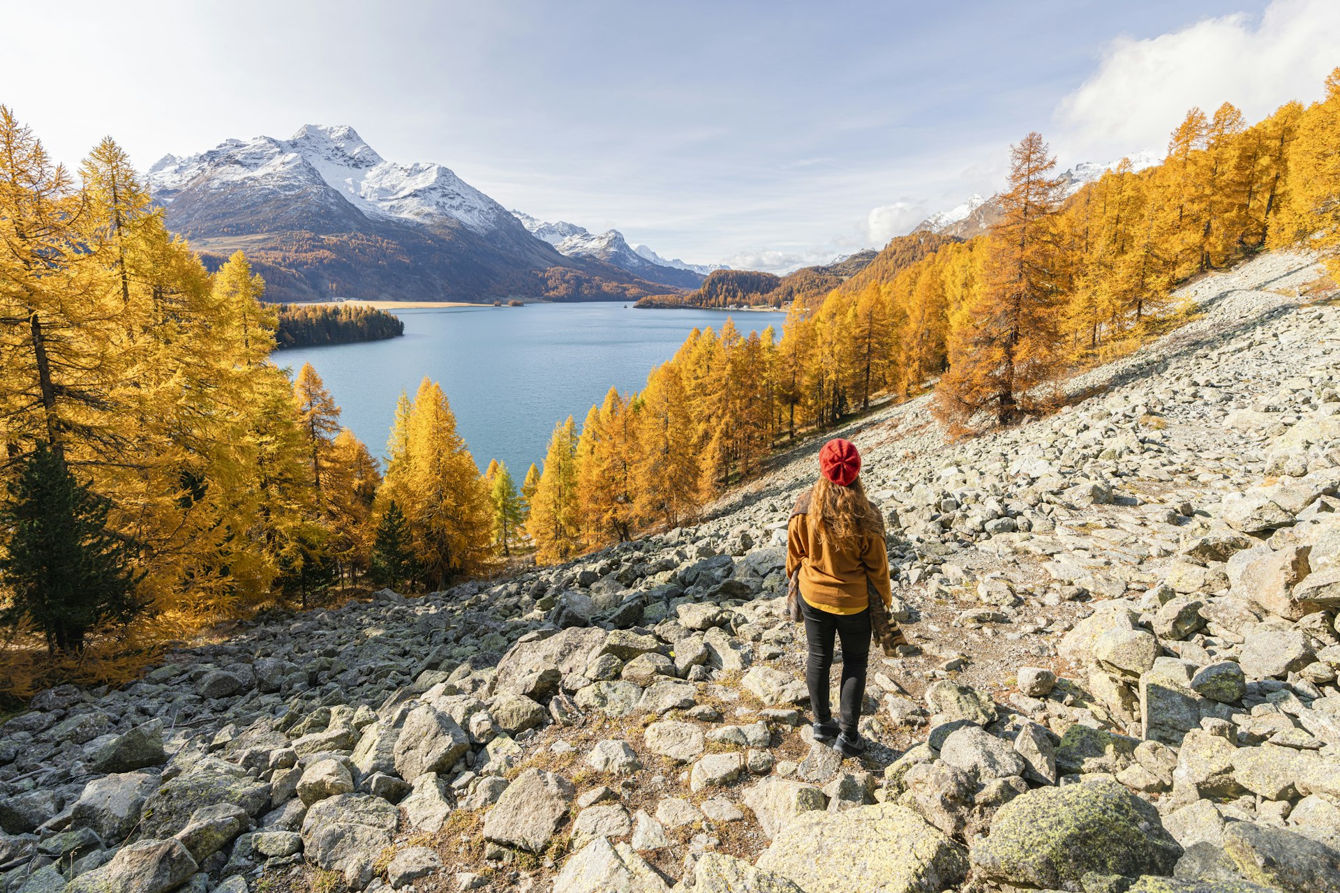 Rear view of a woman looking at La Margna Peak and Lake Sils in autumn, Sils Im Engadin, Maloja region, Canton of Grisons, Switzerland
