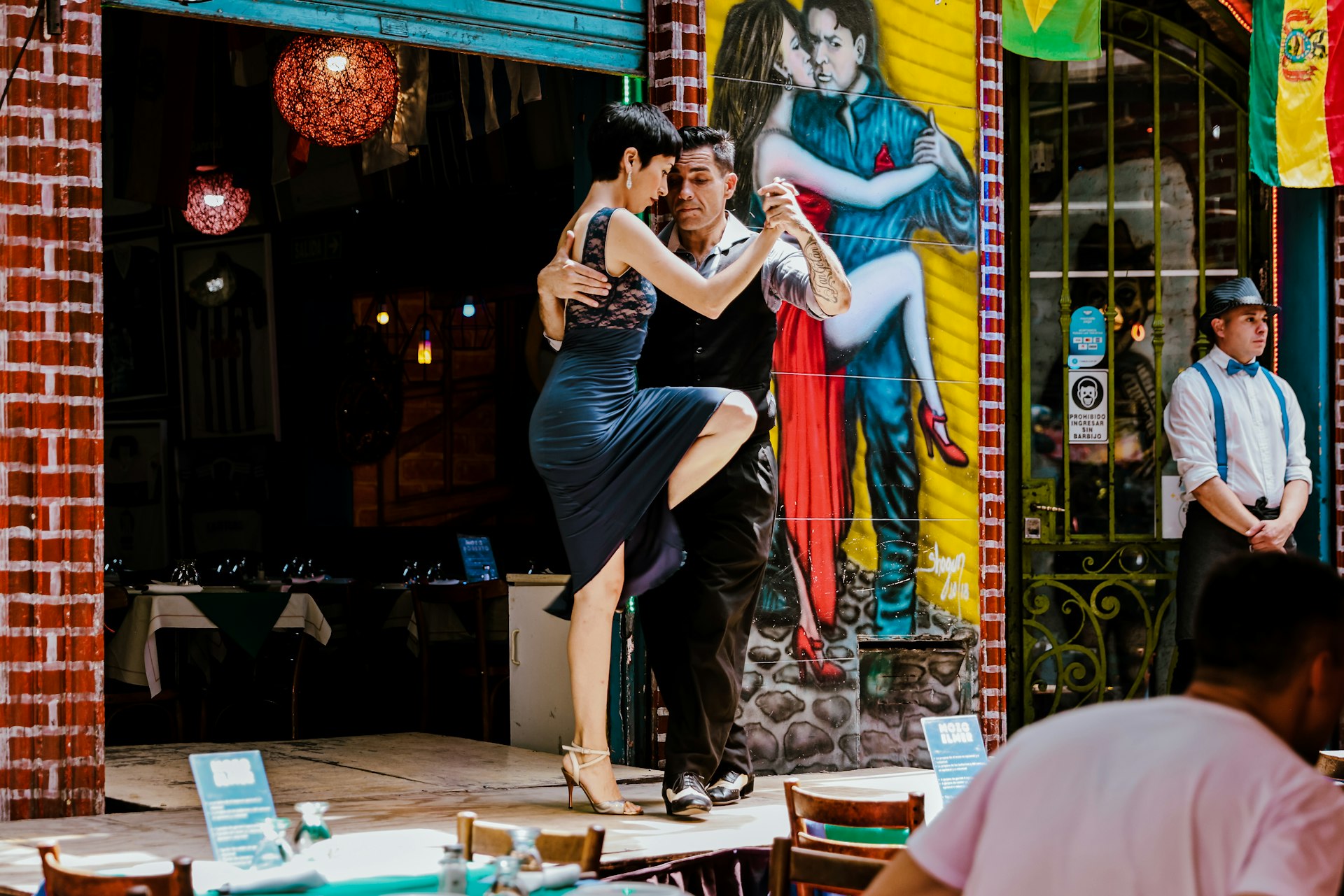 Dancers are performing the Argentine tango on the stage outside a restaurant