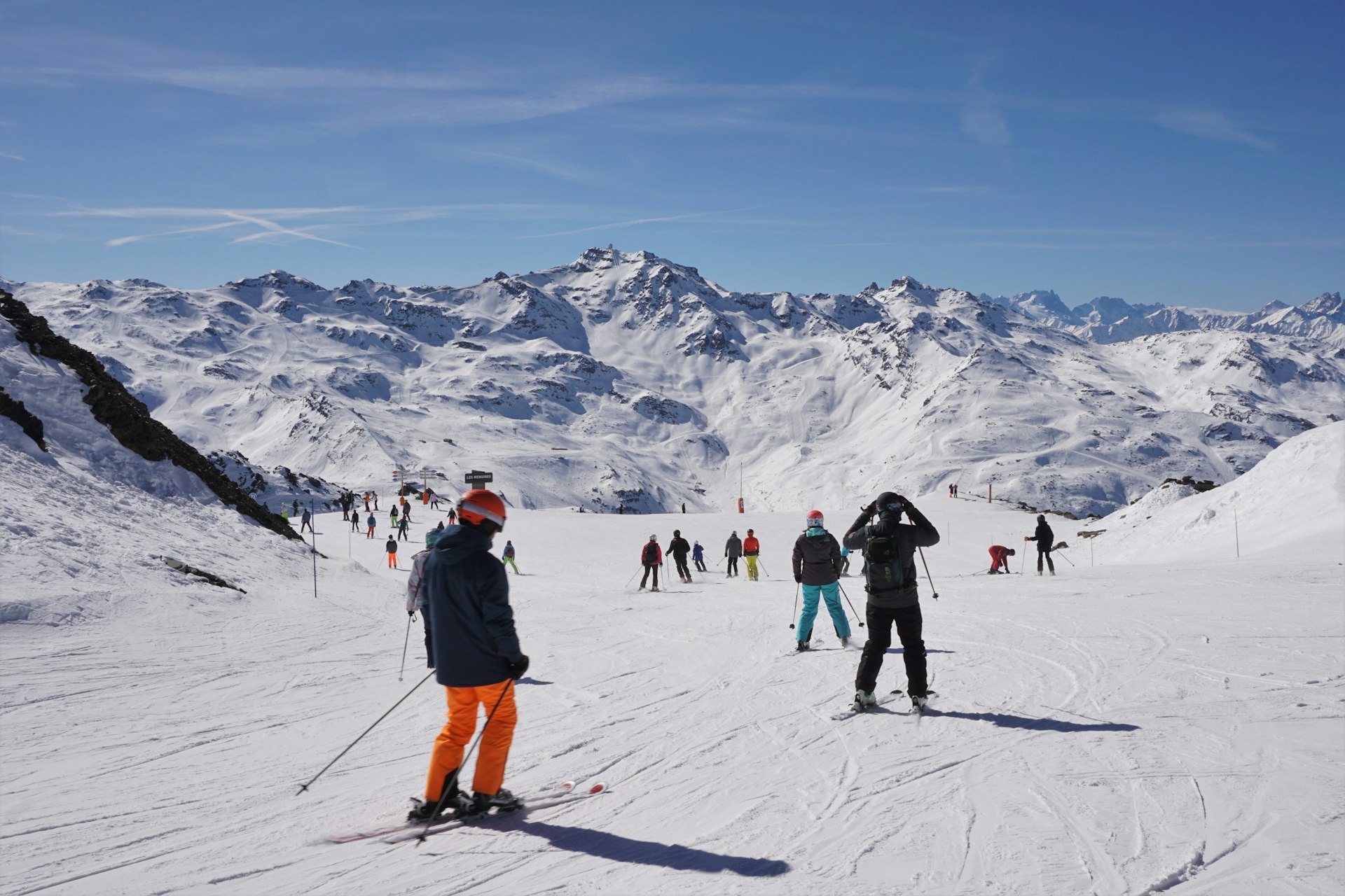 Many people skiing down a piste at Les Menuires in the Trois Vallées (Three Valleys) area in France, on a bright, sunny day
