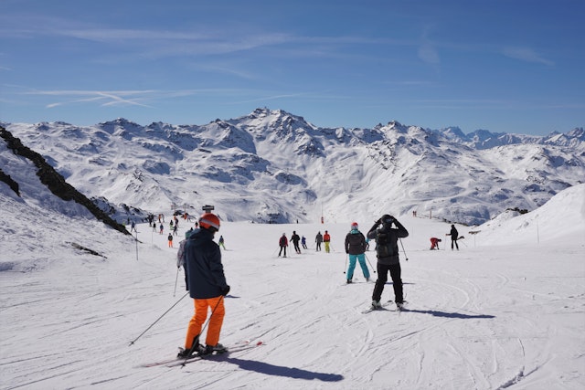 Many people skiing down a piste at Les Menuires in the Trois Vallées (Three Valleys) area in France, on a bright, sunny day