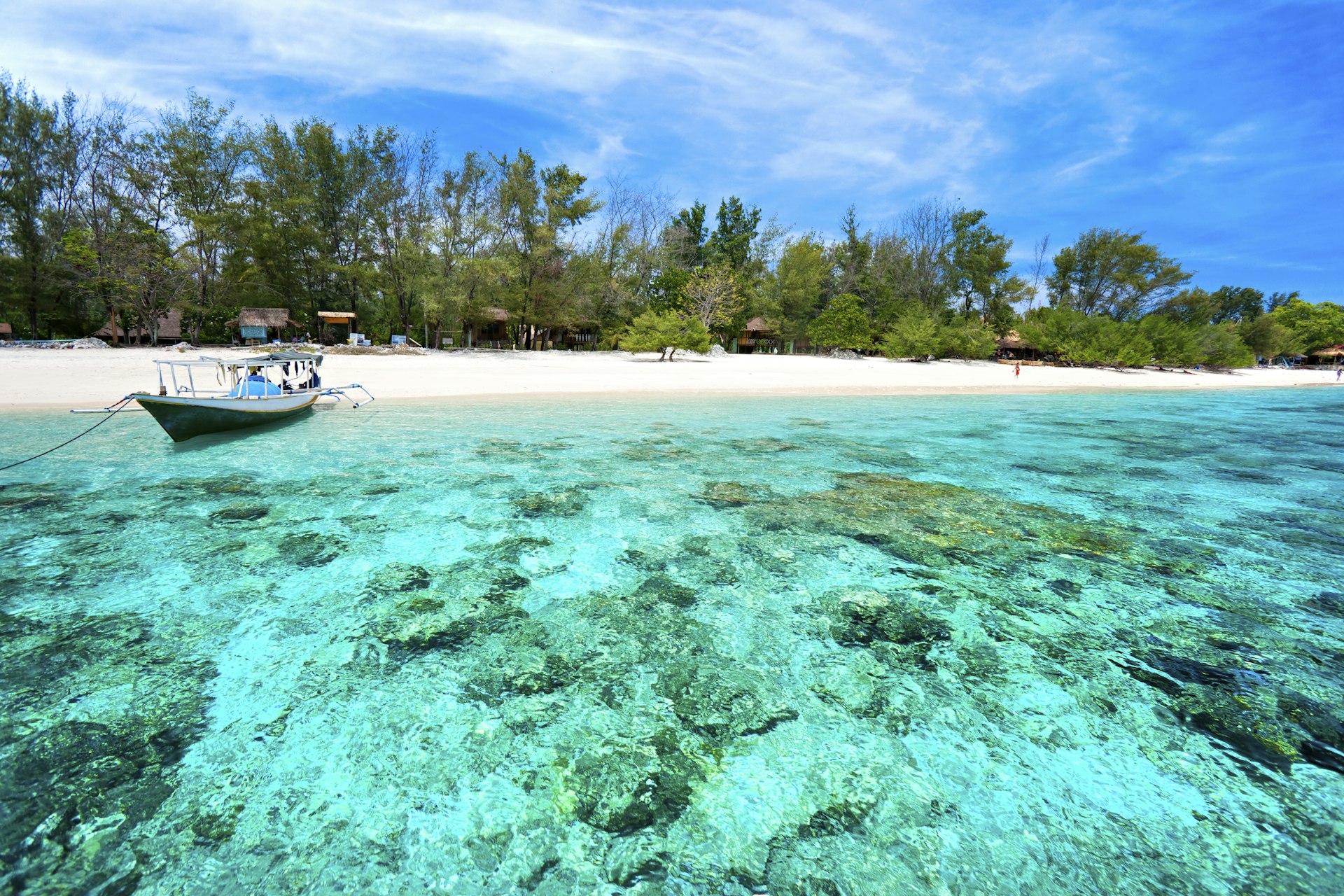 A boat sits near the sandy shore in clear turquoise waters