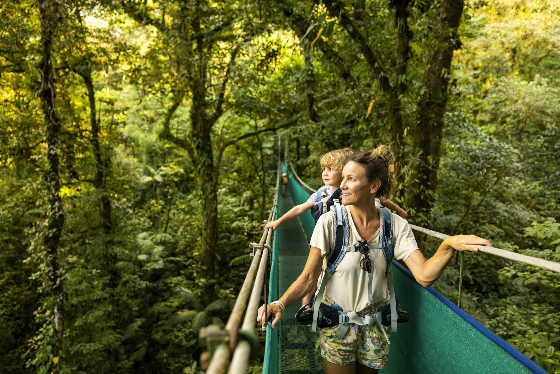 A mother and young child hiking across a suspension bridge in Costa Rica