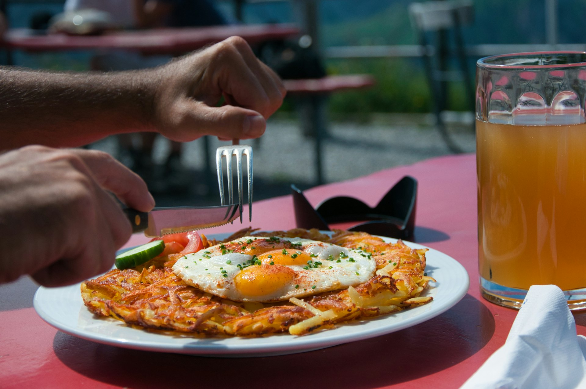 Man eating a rösti at a table in the sunshine