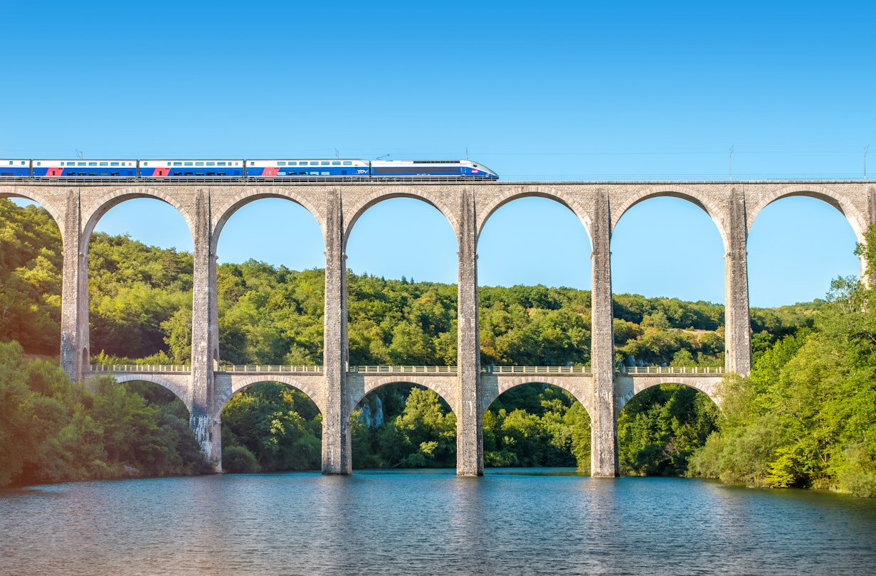 Cize, France - July 9, 2015: French high speed train TGV operated by SNCF, national rail operator on Cize-Bolozon viaduct bridge in Ain, Rhone-Alpes region in France. This train was developed during the 1970s by GEC-Alsthom and SNCF. A TGV test train set the record for the fastest wheeled train, reaching 574.8 km/h (357.2 mph) on 3 April 2007. Viaduct of Cize-Bolozon in summer season in Bugey along Ain river. This viaduct is a combination rail and vehicular viaduct crossing the Ain gorge. An original span built in the same location in 1875 was destroyed in World War II. Reconstructed as an urgent post-war project due to its position on a main line to Paris, the new viaduct reopened in May 1950. It carries road and rail traffic at different levels.
481529752
Brand-name, European Culture, Travel, People Traveling, Tourism, High Speed Train, Locomotive, Elevated Road, High Speed, Arch Bridge, Railway Bridge, Elevated Railway Track, Viaduct, Railroad Crossing, Stone Material, Symmetry, Crossing, Scenics, Arch, Bullet Train, Majestic, Journey, Blue, Ancient, Old, Pattern, French Culture, Architecture, Transportation, Nature, Rural Scene, Panoramic, Ain, Rhone-Alpes, France, Europe, Tree, Summer, Mountain, Hill, Landscape, Sky, River, Water, Railroad Track, Bridge - Man Made Structure, Monument, Train, Mode of Transport, Stone Bridge, SNCF, TGV, Alstom, Bugey