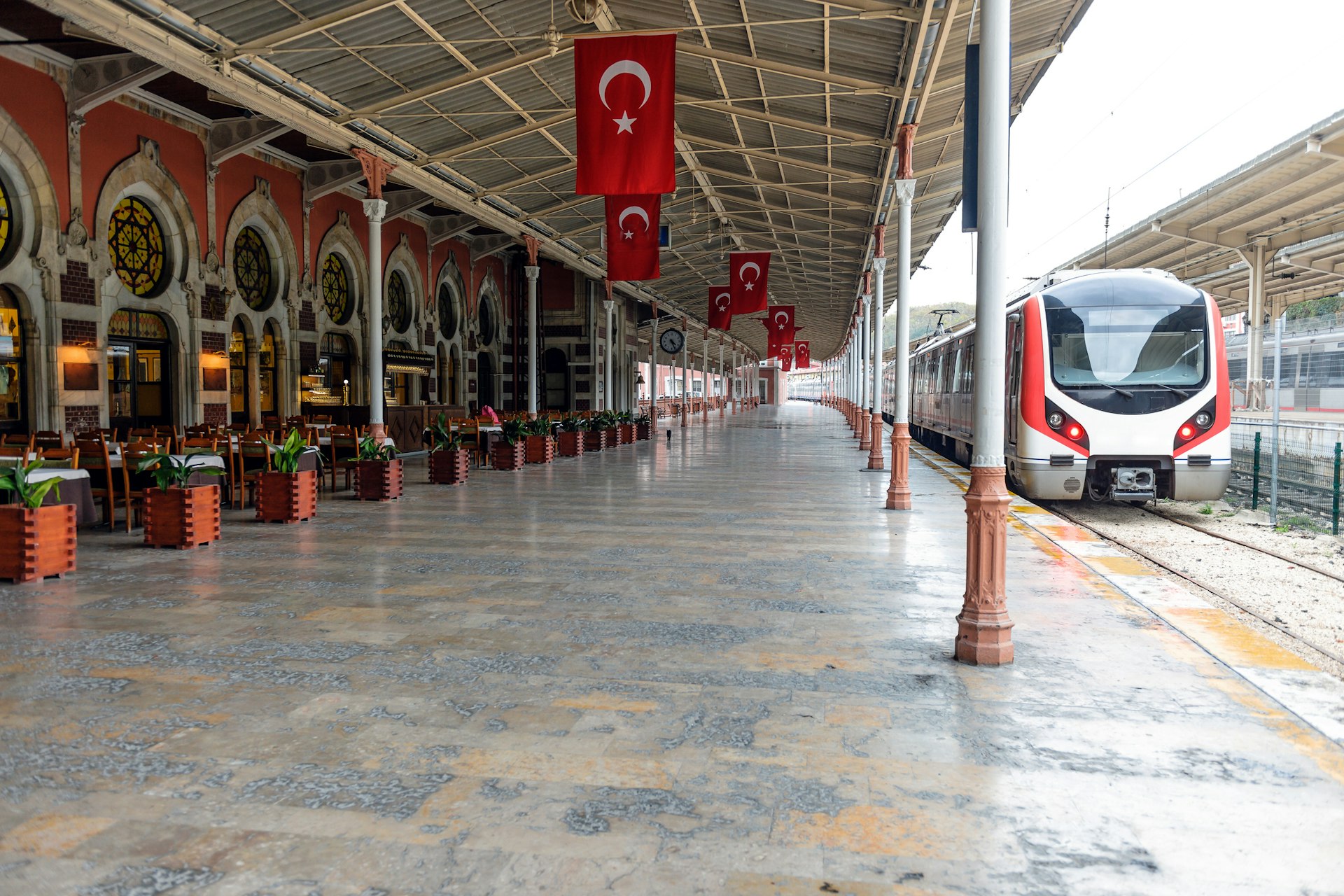 An ornate station platform with Turkish flags hanging from the ceiling 