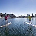 Man and women paddle stand up paddleboards through the Inner Harbour towards the Parliament Buildings. © Aaron Black / Getty Images RFC