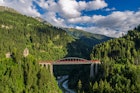 A train passing over a bridge across the Trisanna river in the Tyrolean Mountains