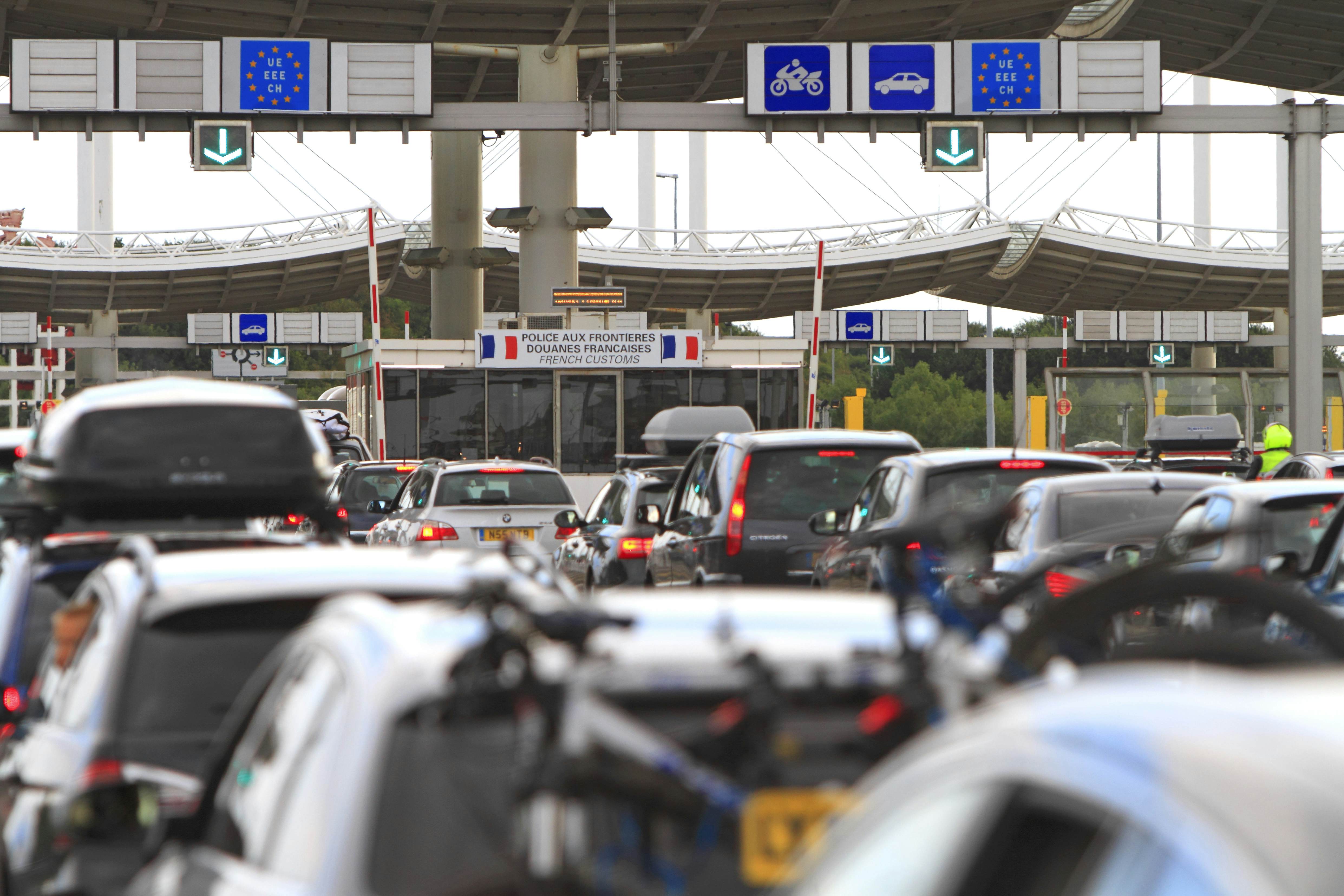 A queue of stationary vehicles in several lines in front of a sign that says 