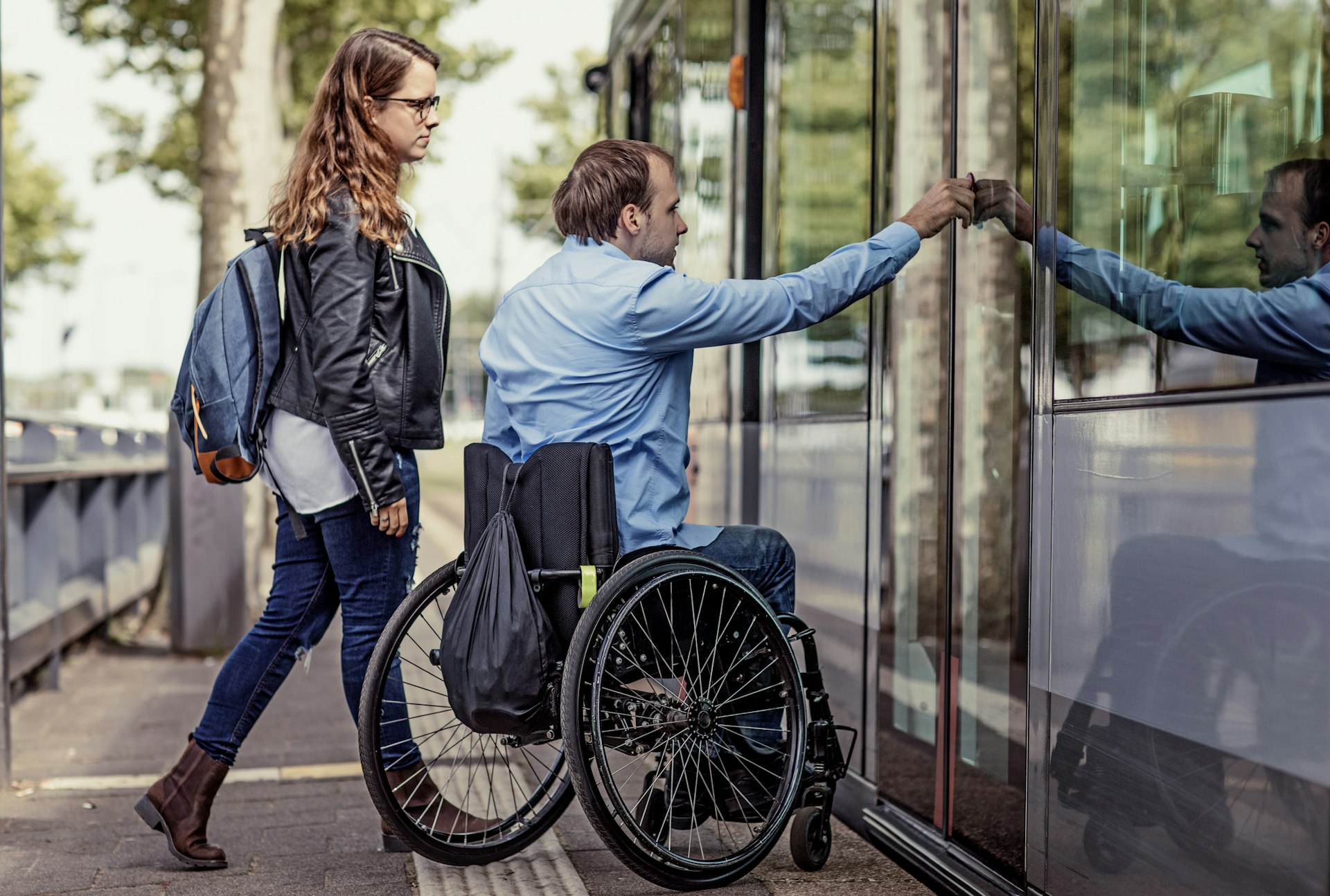A man in a wheelchair boarding a tram with his girlfriend in the Netherlands